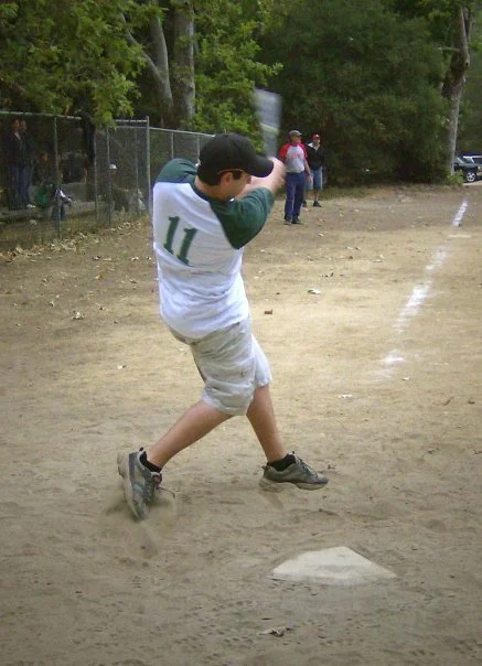 A young boy wearing a baseball uniform with the number 11, batting at a baseball field.