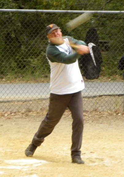 A man swinging a baseball bat at a ball in a baseball field.