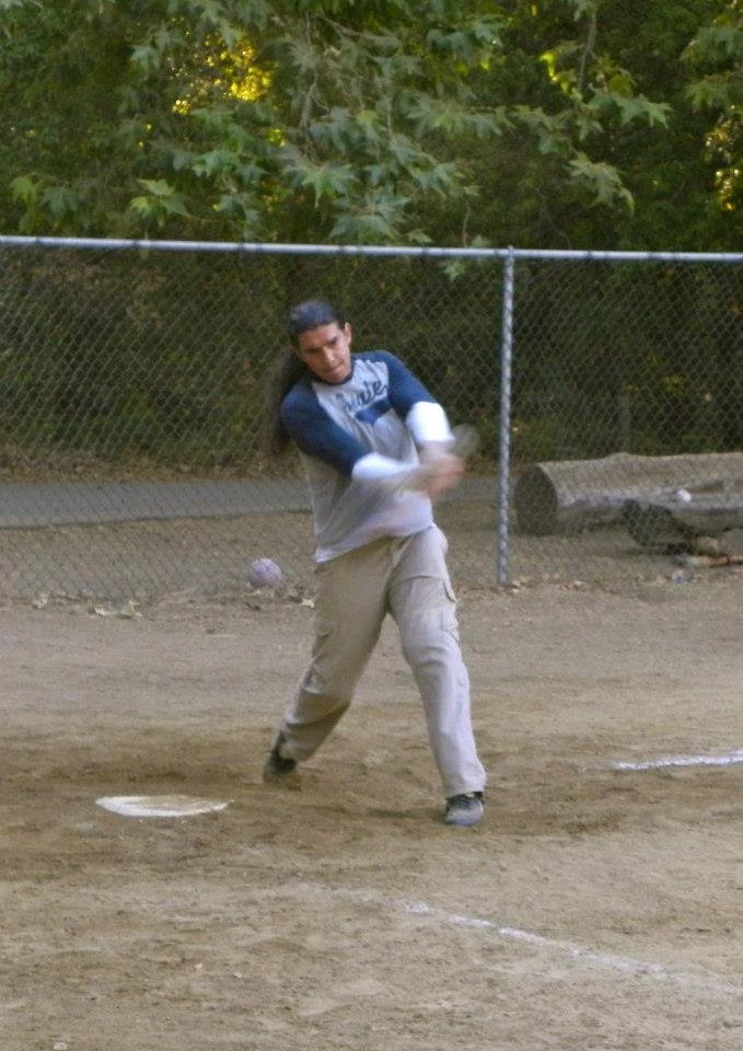 A person swinging a bat during a baseball game at a baseball field.