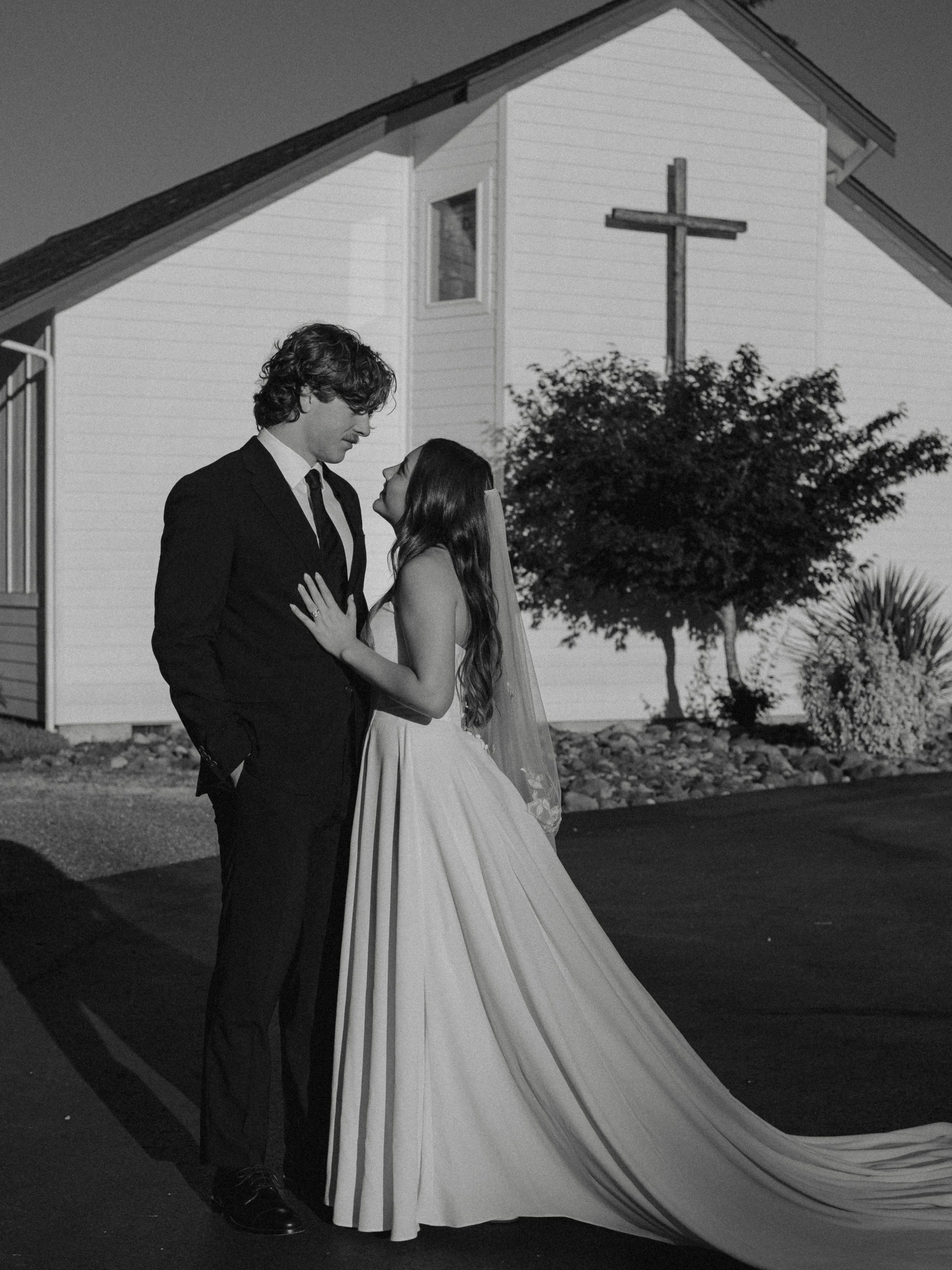 Couple getting married in front of a church. Man in a tux, woman in a bridal dress and veil. 