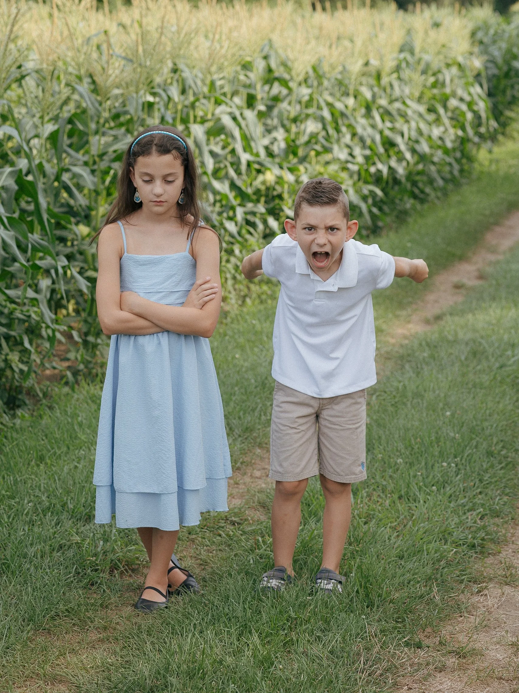 Brother and sister in a corn field making mad faces