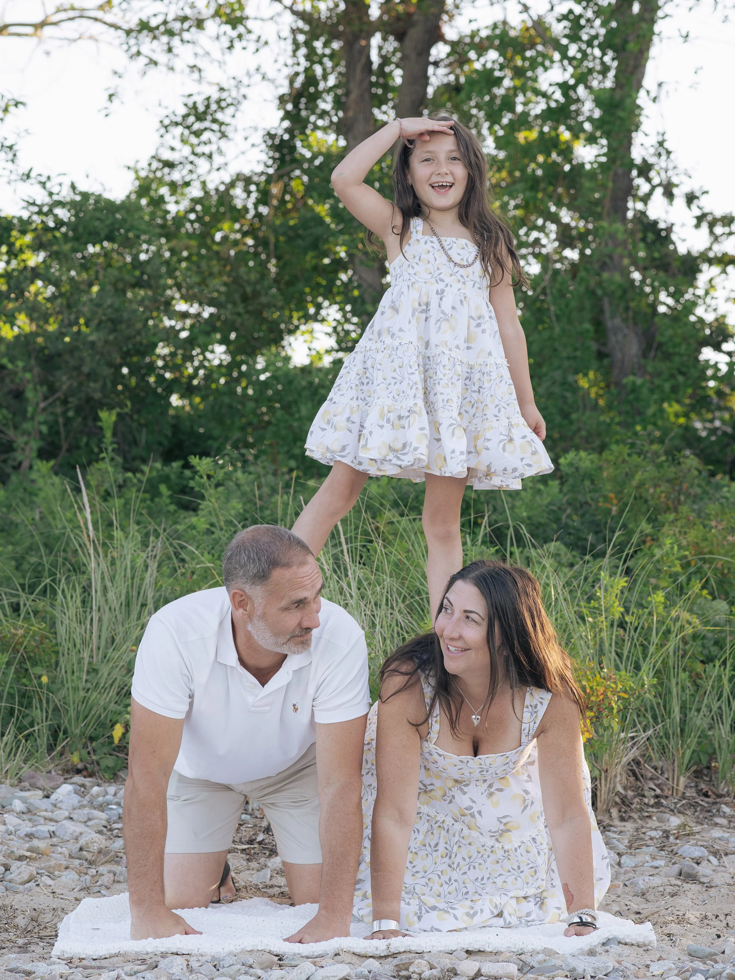 Father and mother with daughter on their backs making a pyramid at the beach