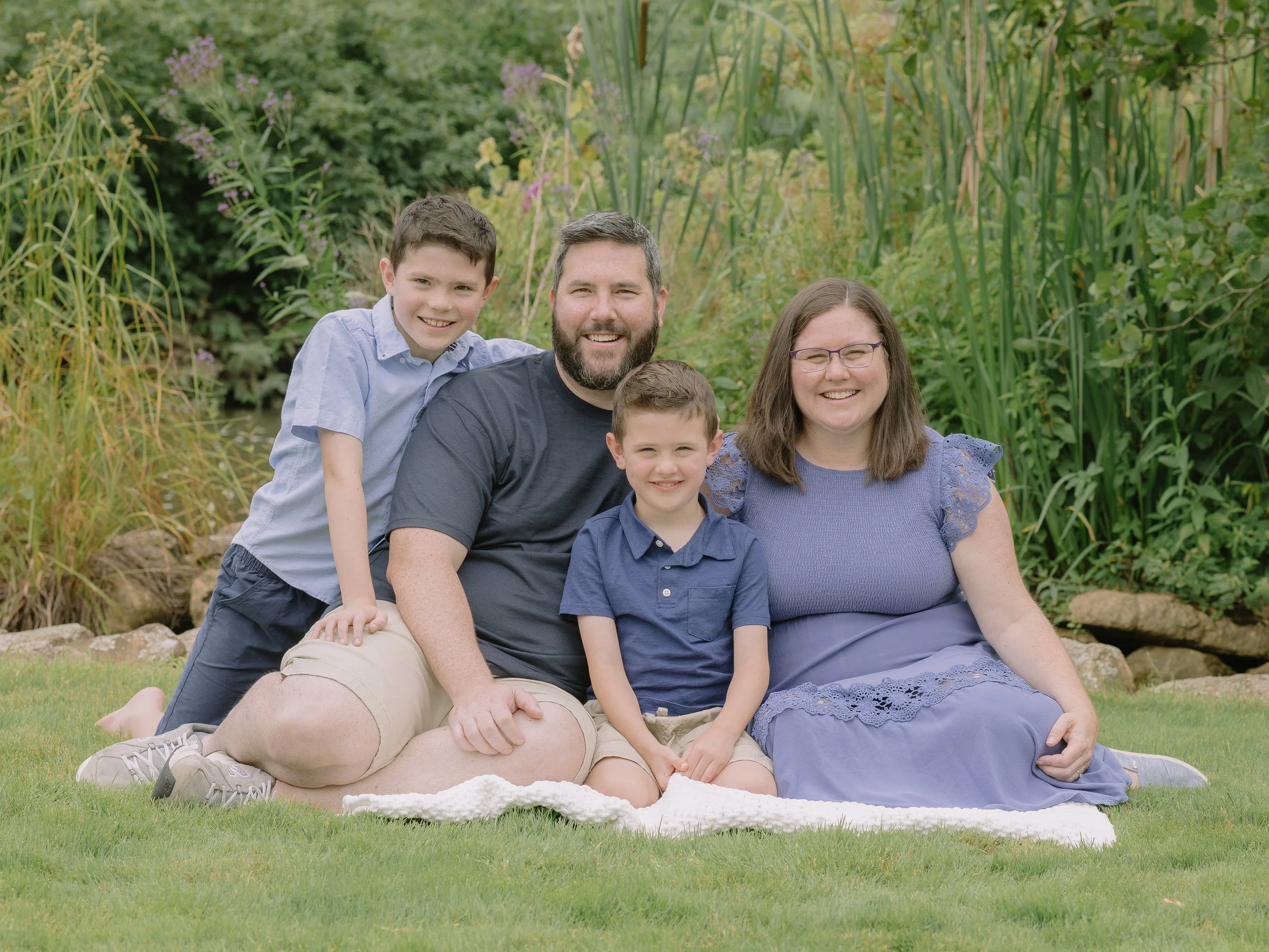 Family of four sitting in a grassy spot with blue outfits