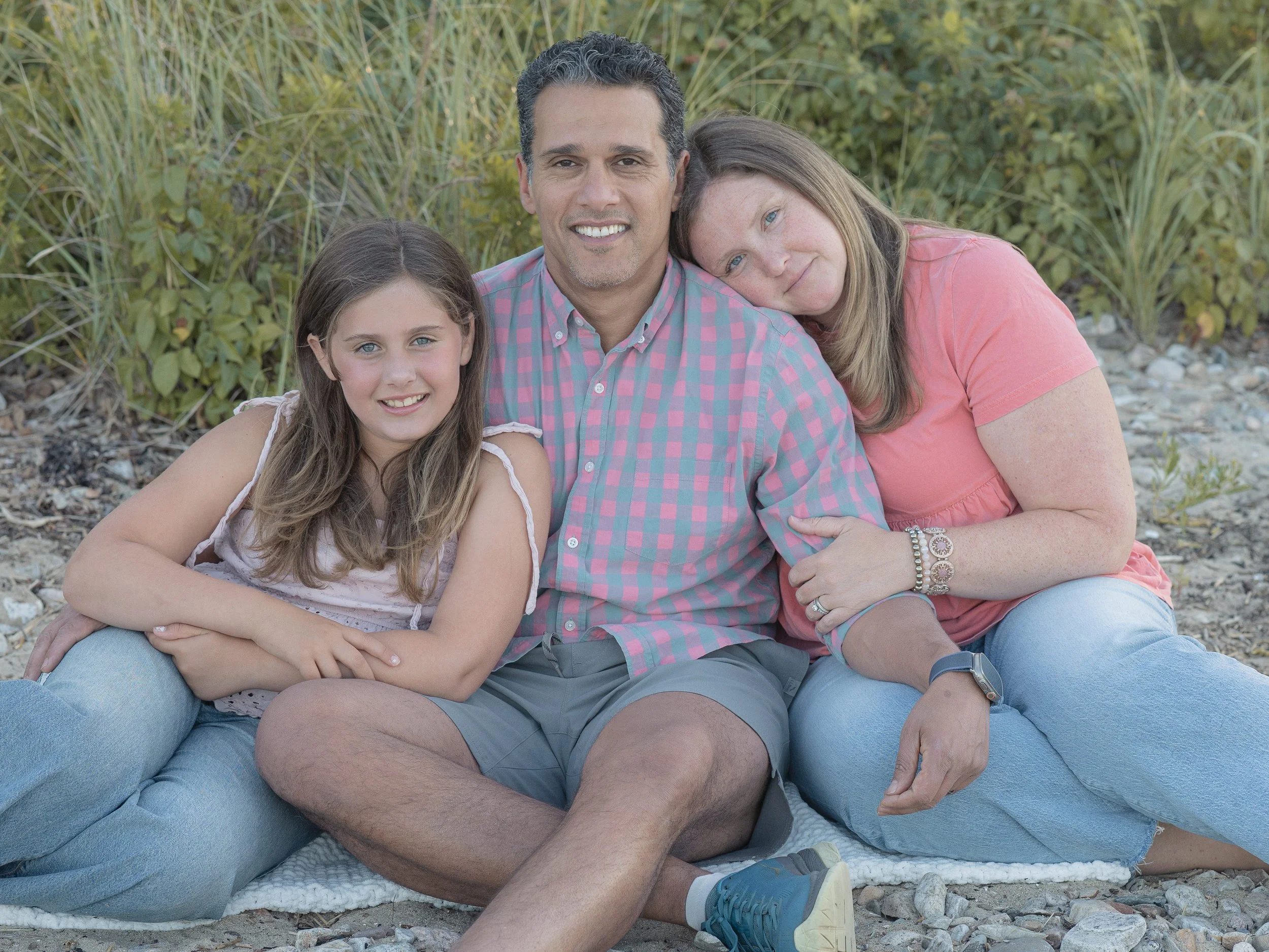 A family of three in matching outfits at the beach 