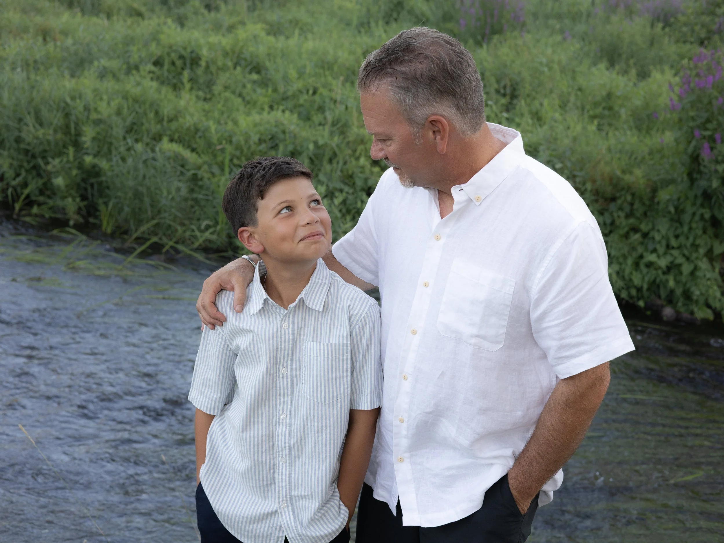 Father and son sharing a moment in front of a river in a park