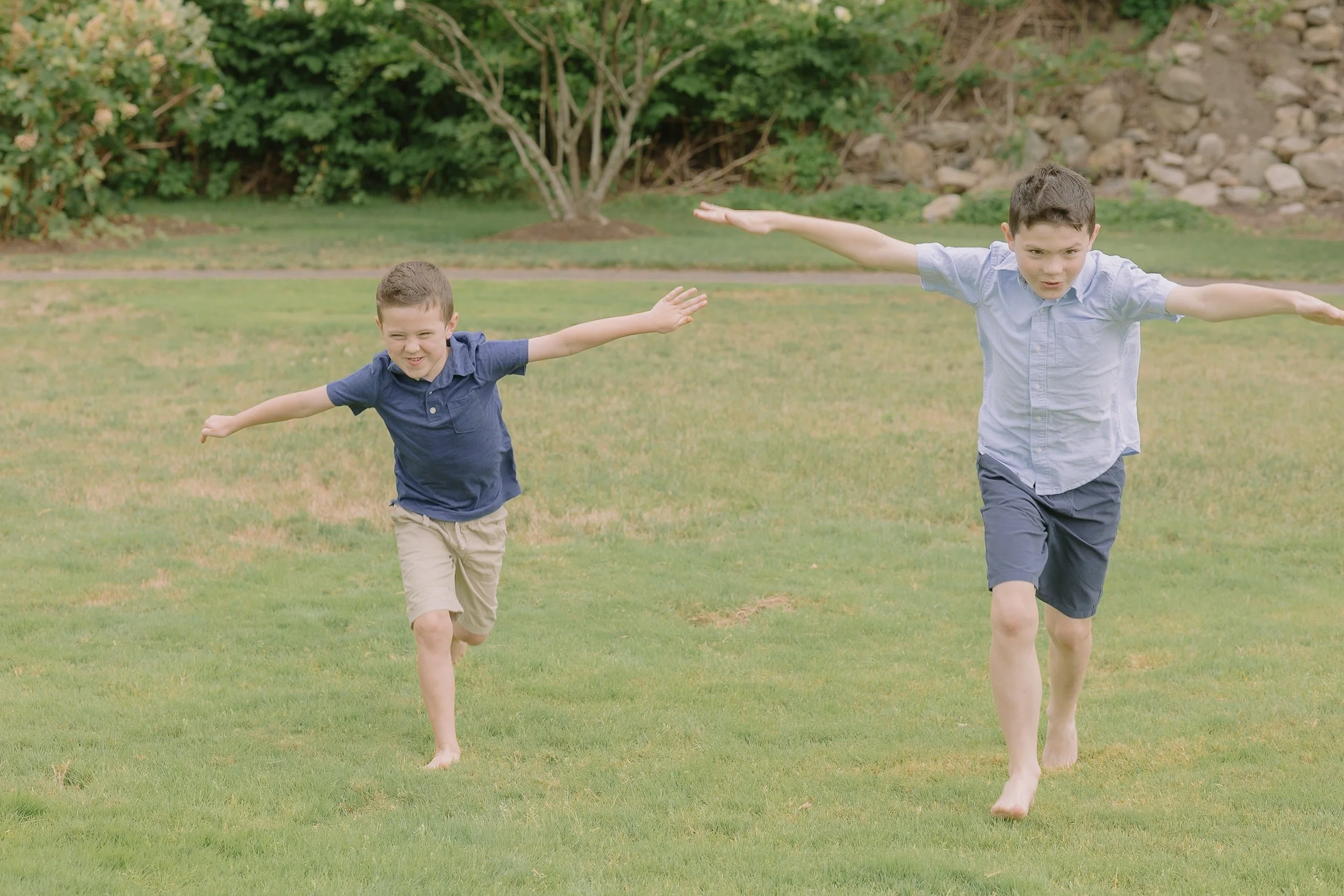 Two young boys having an airplane race in a park with matching outfits