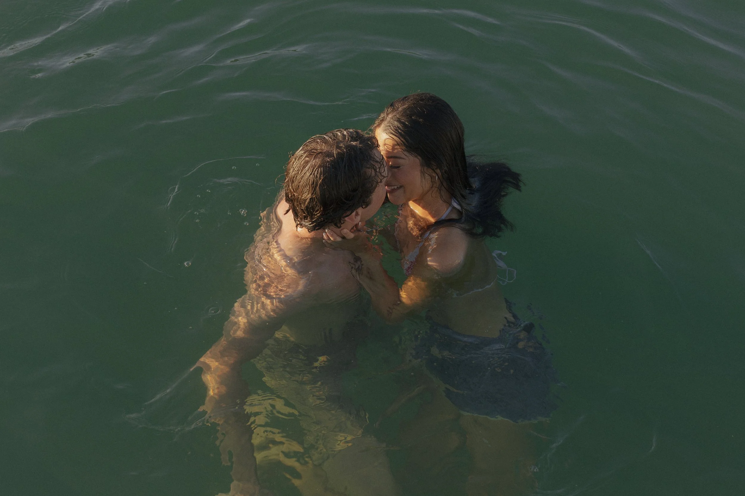 Man and woman embracing in a lake at sunrise