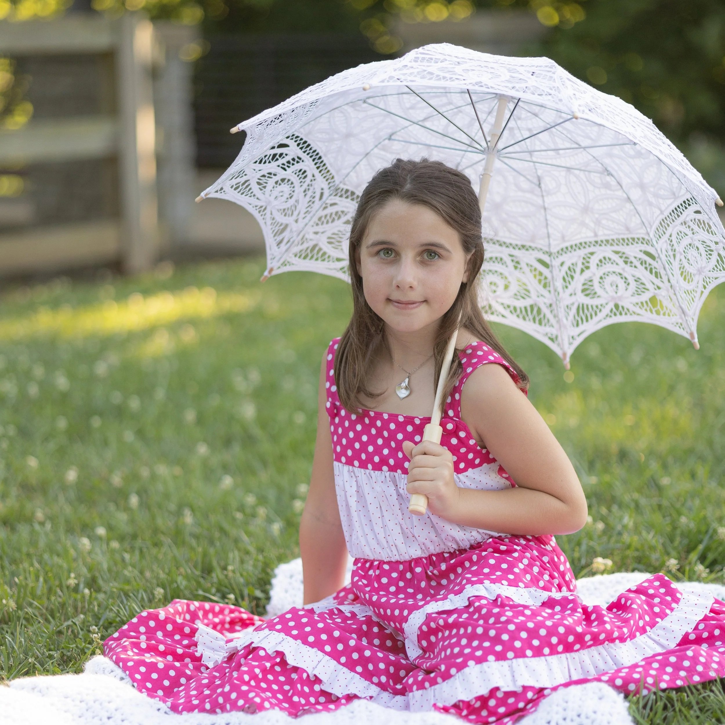 Young girl with a lace parasail in a pretty pink dress