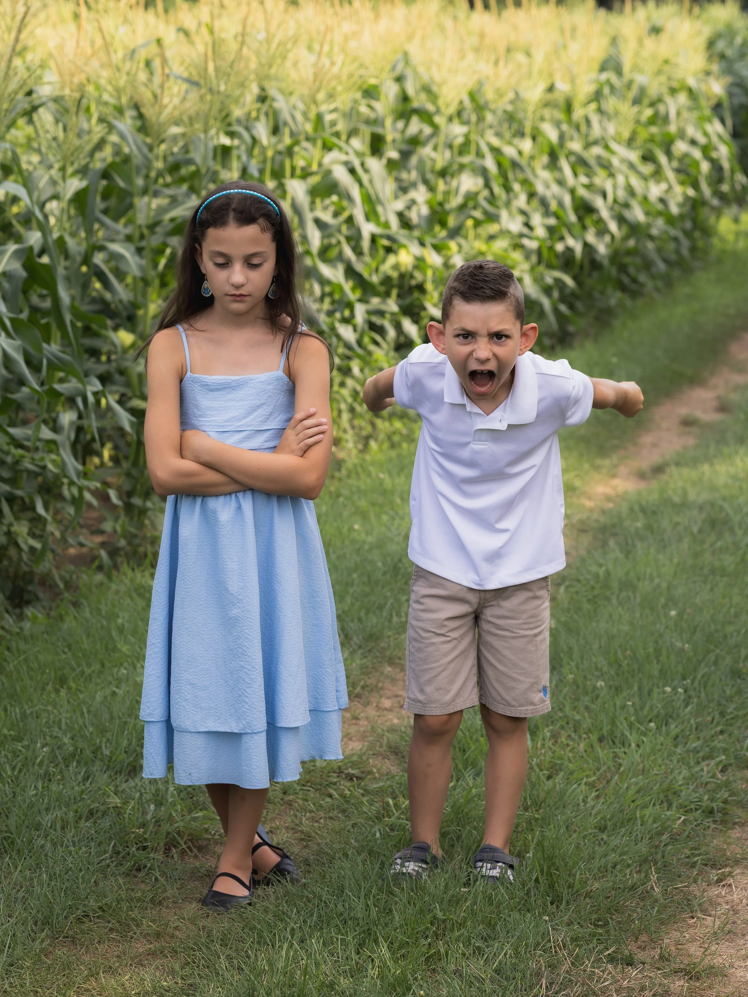 Brother and sister in a corn field making mad faces