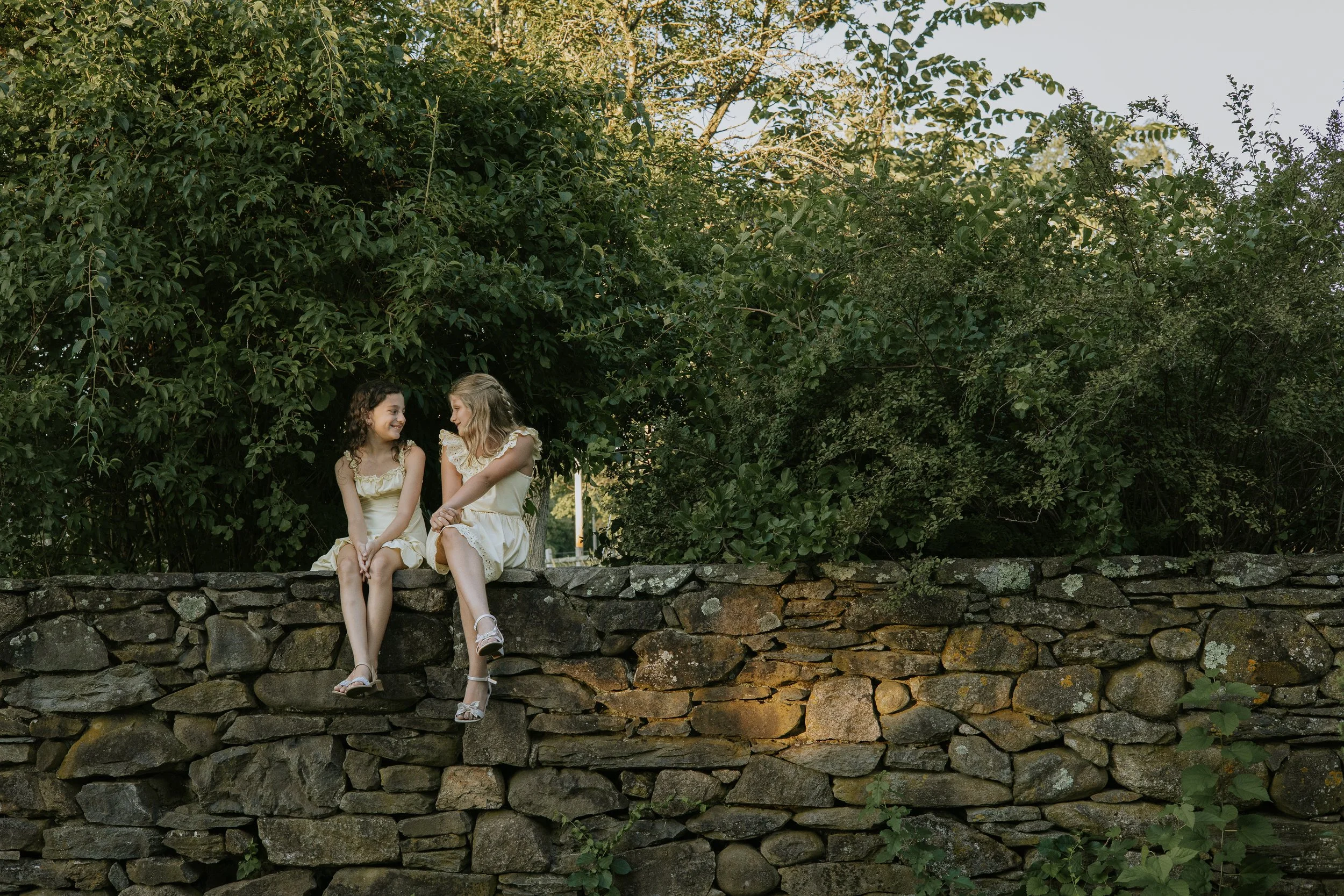 Two young girls having a conversation on a rock wall