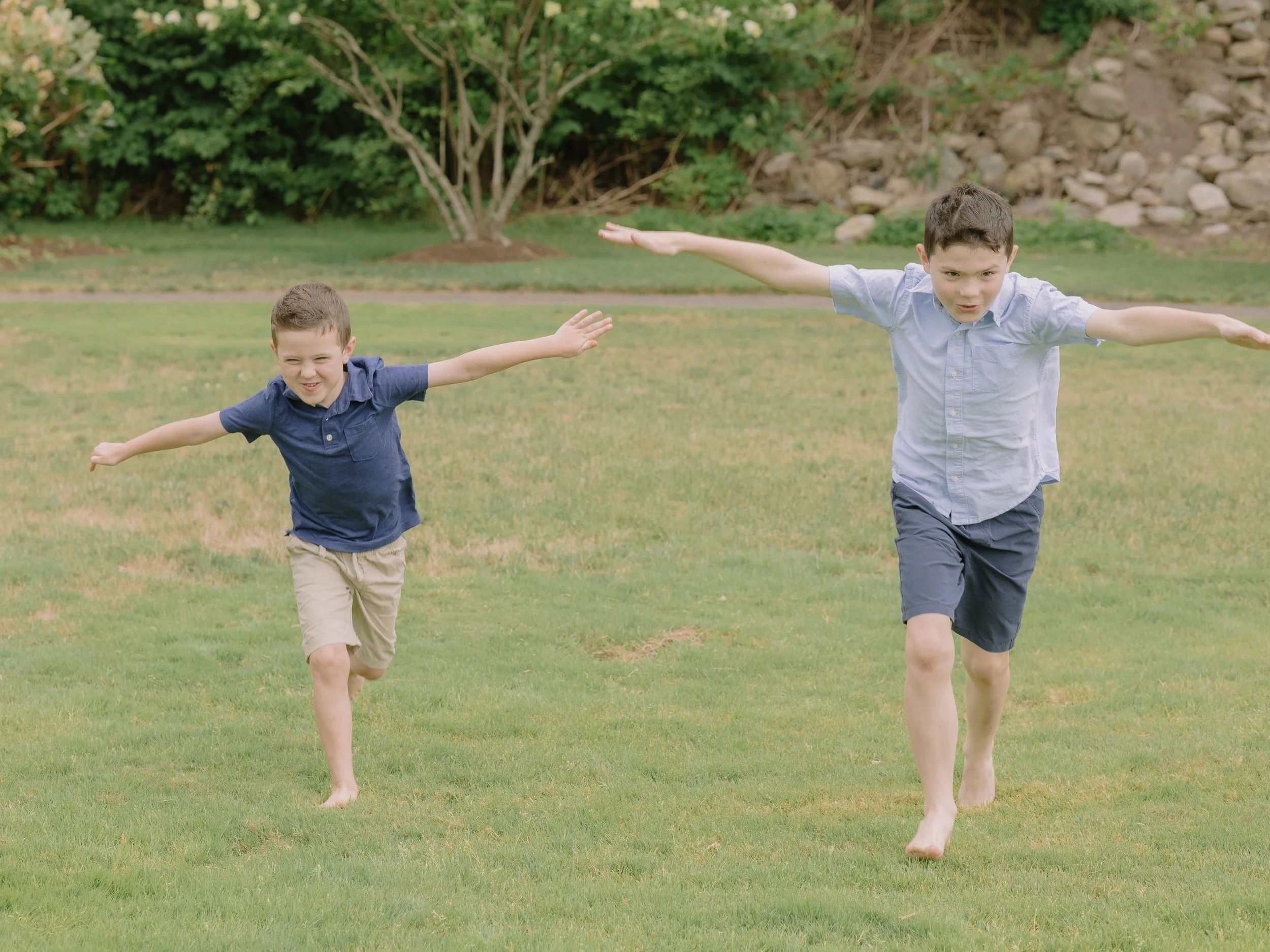 Two young boys having an airplane race in a park with matching outfits