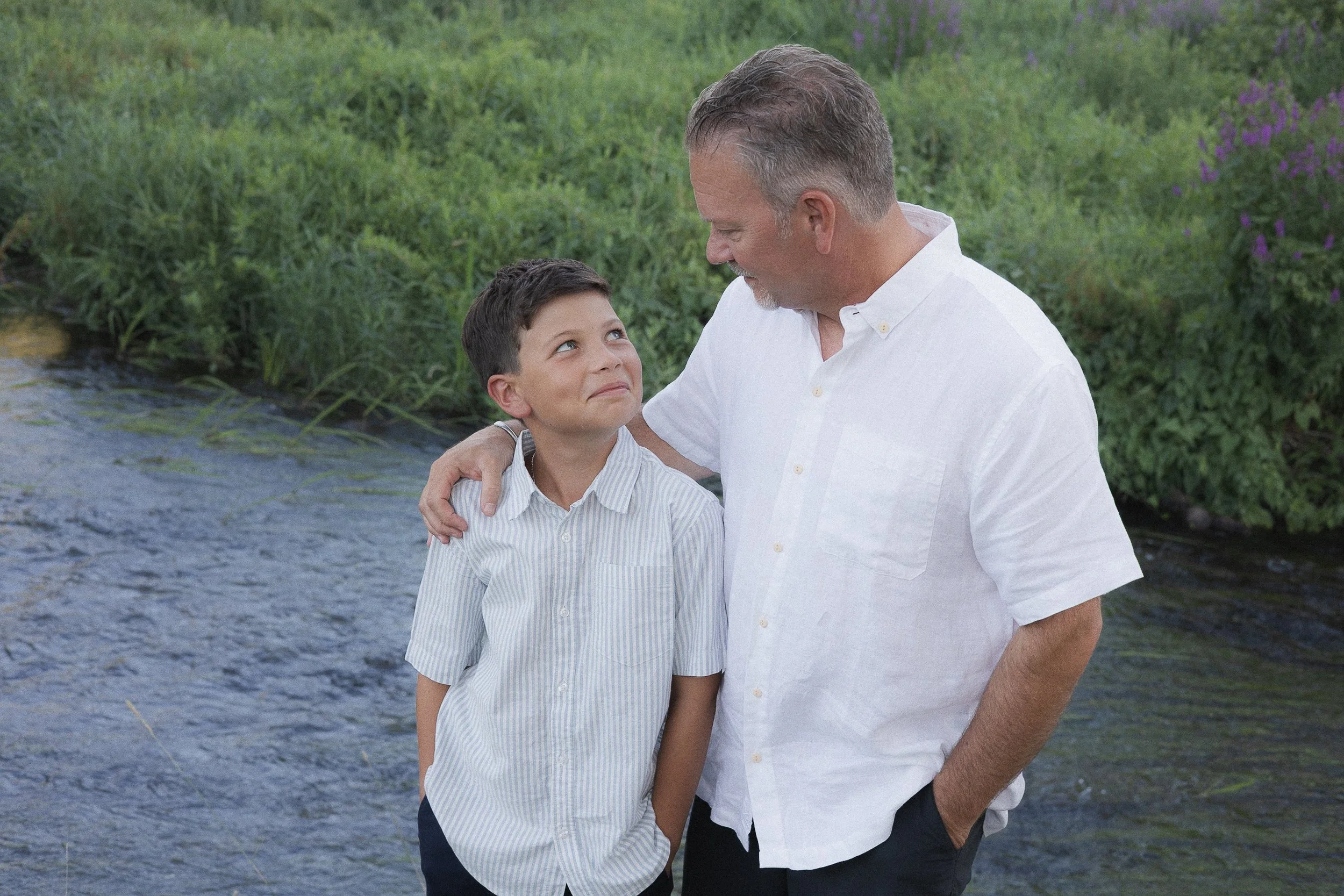 Father and son sharing a moment in front of a river in a park