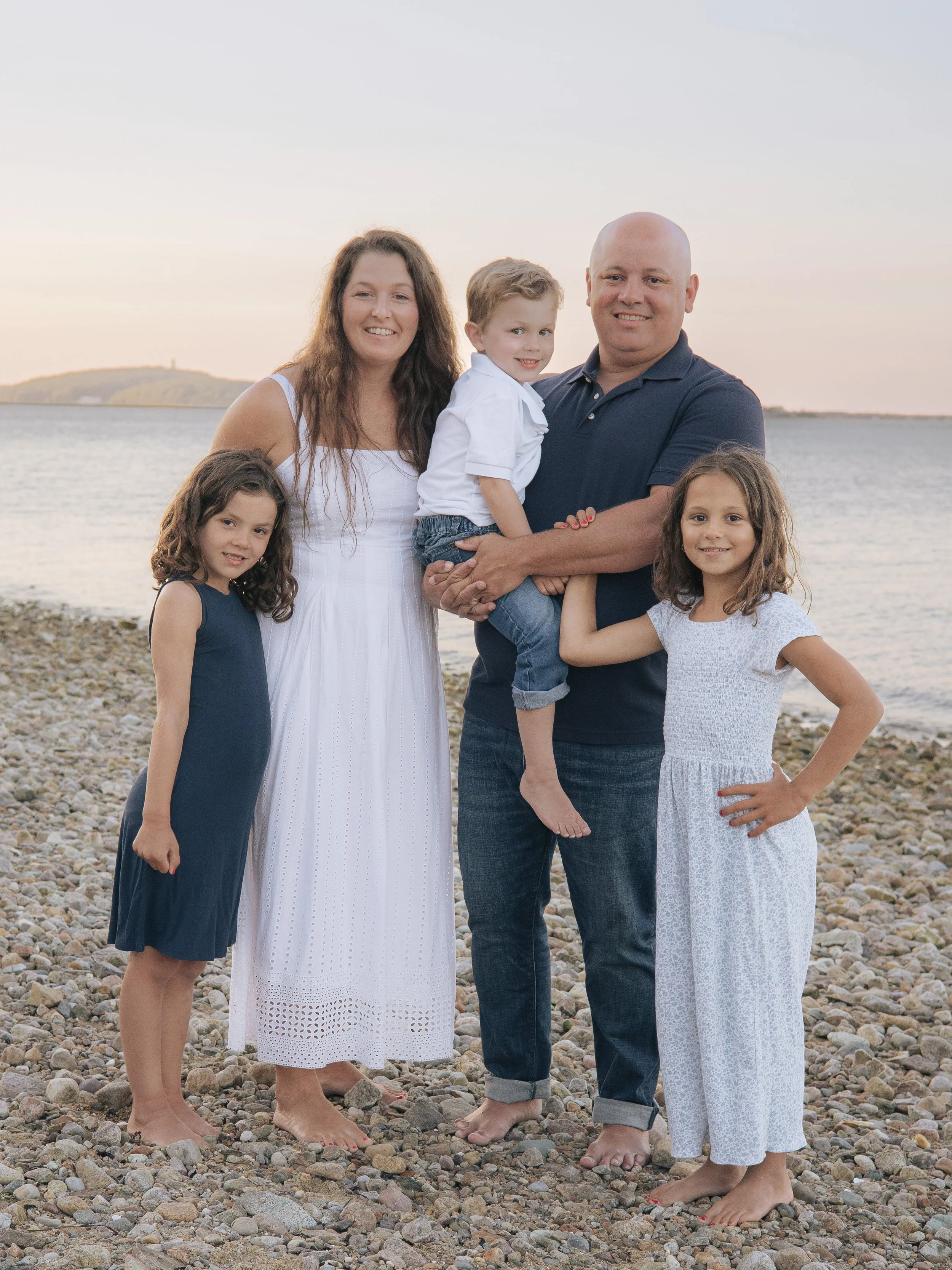 Family of five at the beach in navy and white outfits