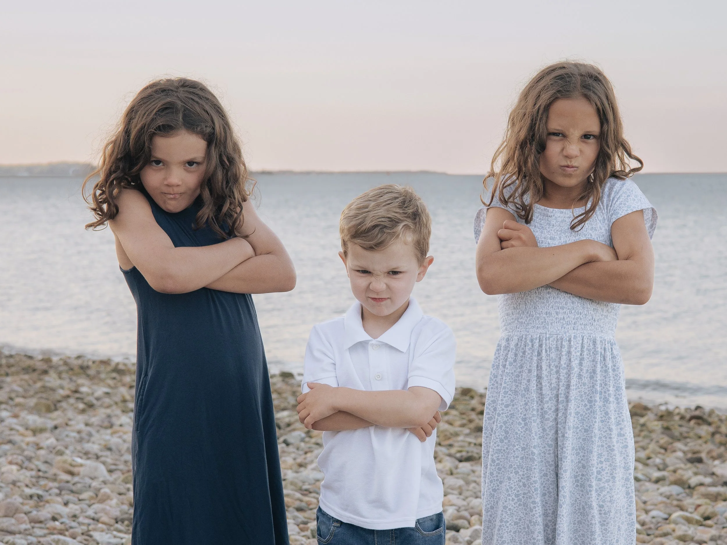 Three siblings at the beach making mad faces for the camera
