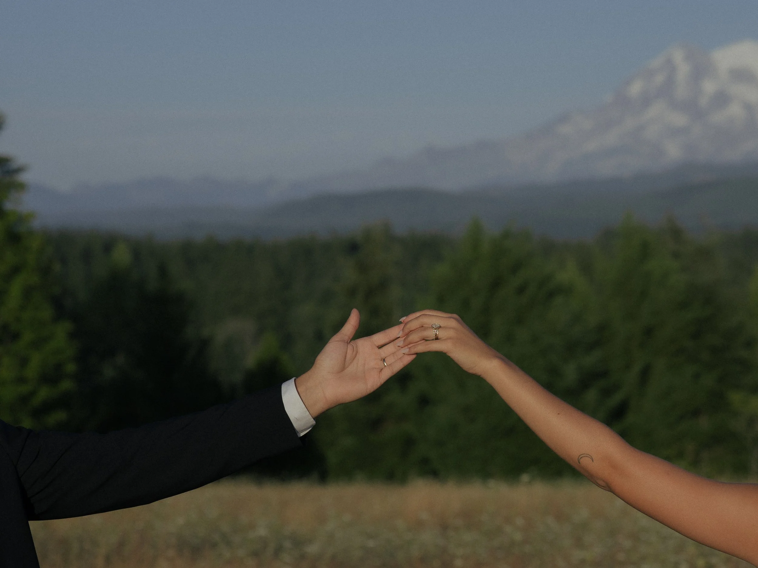 Man and woman touching fingertips with mountains in the background. 