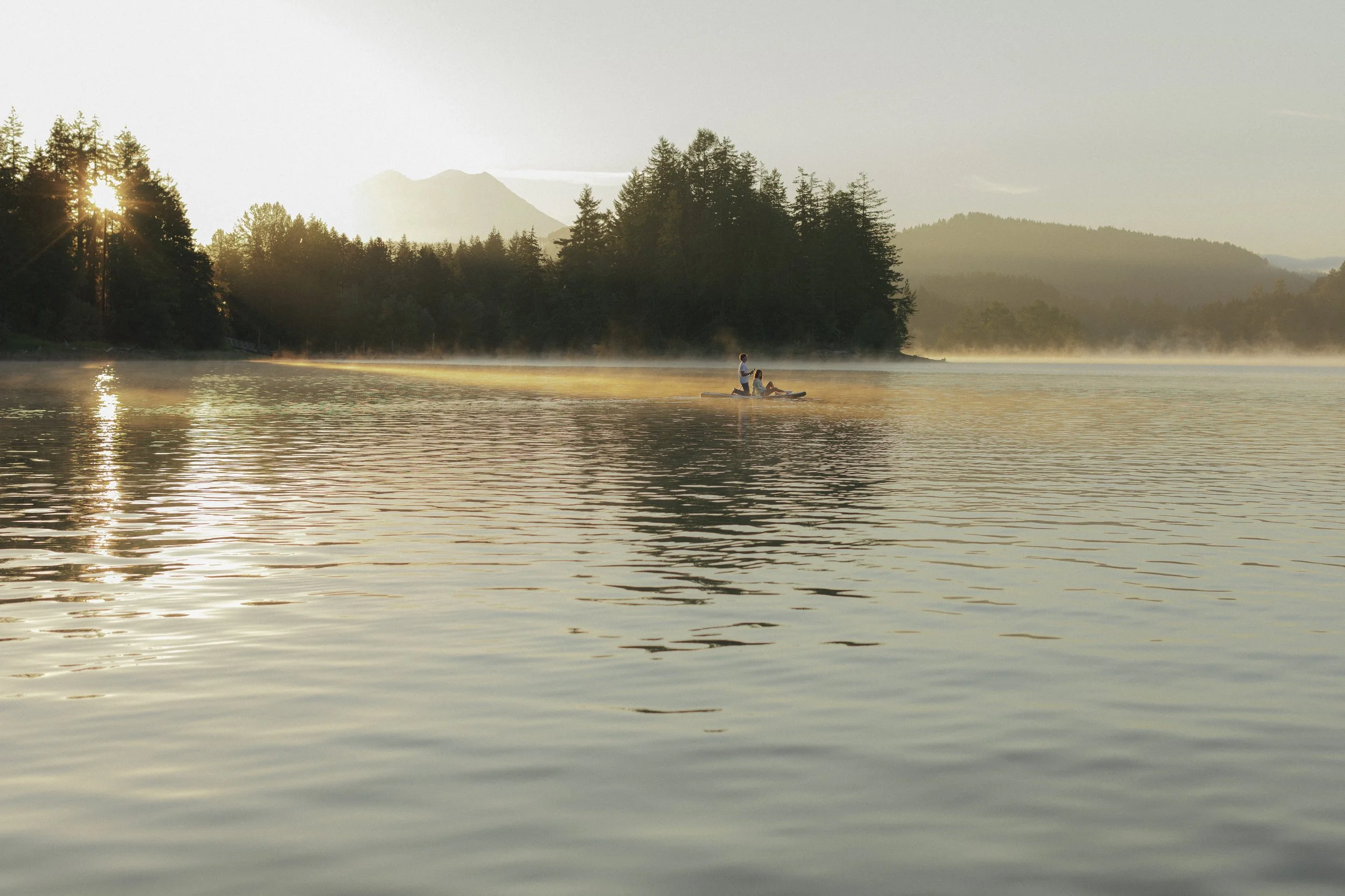 Couple on a paddle board on a lake at sunrise