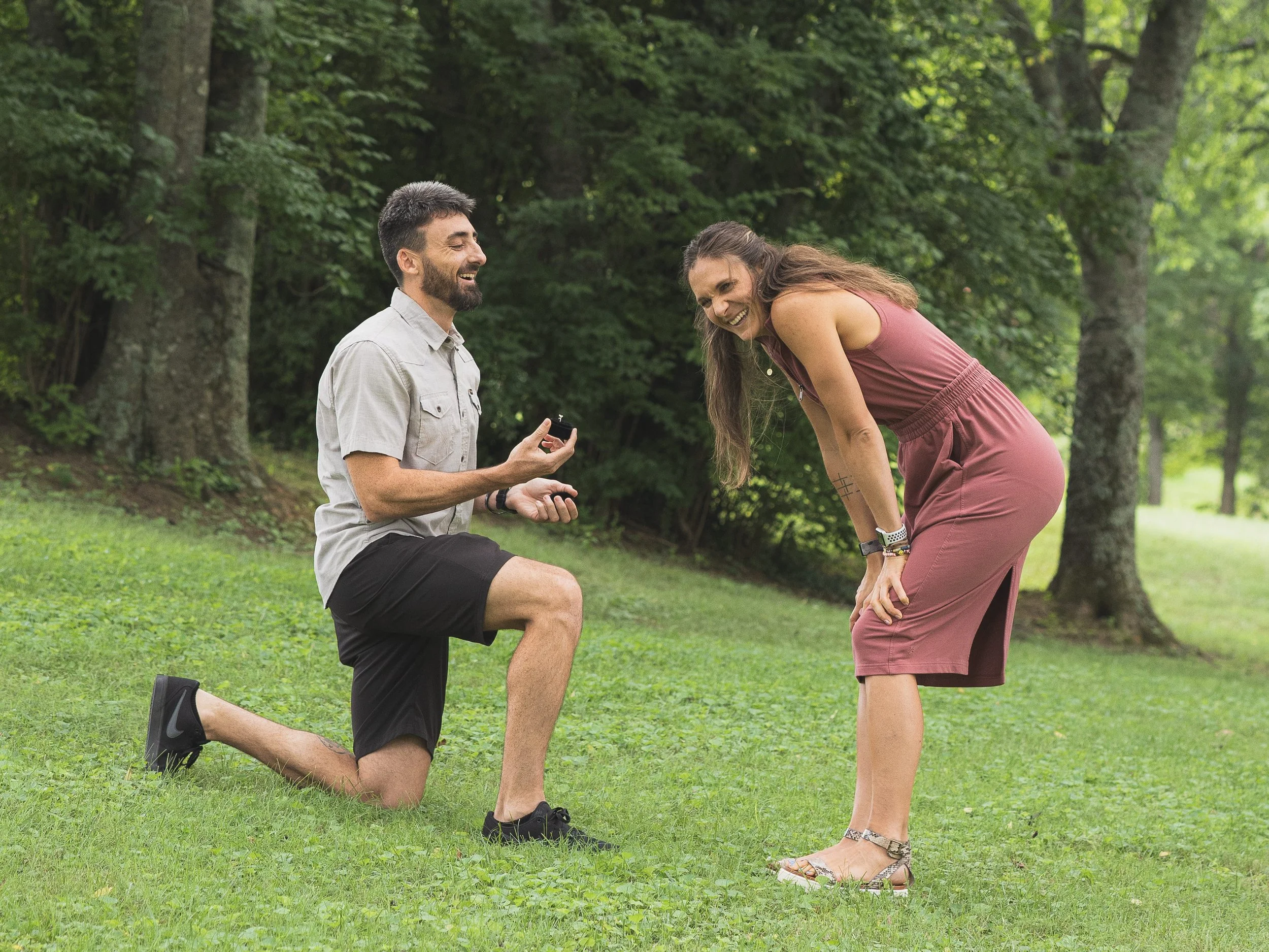 Man down on one knee proposing to a woman in a park