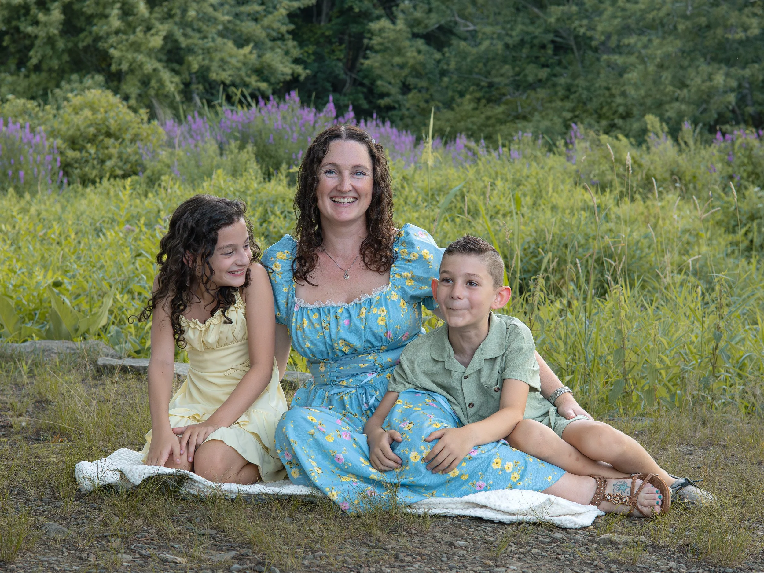 Mother and two kids in front of summer flower blooms
