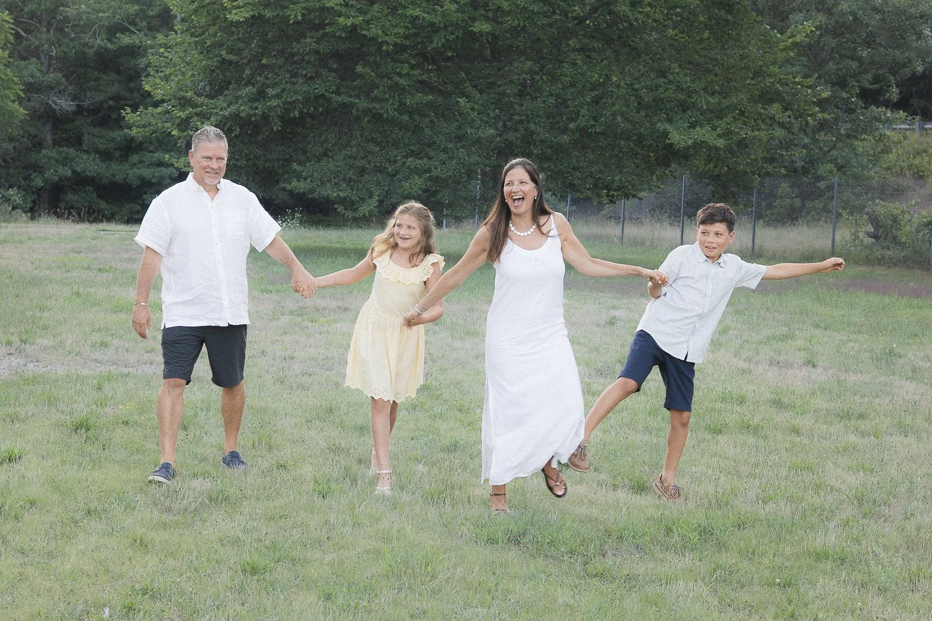 Family holding hands in coordinated outfits in a field of green grass