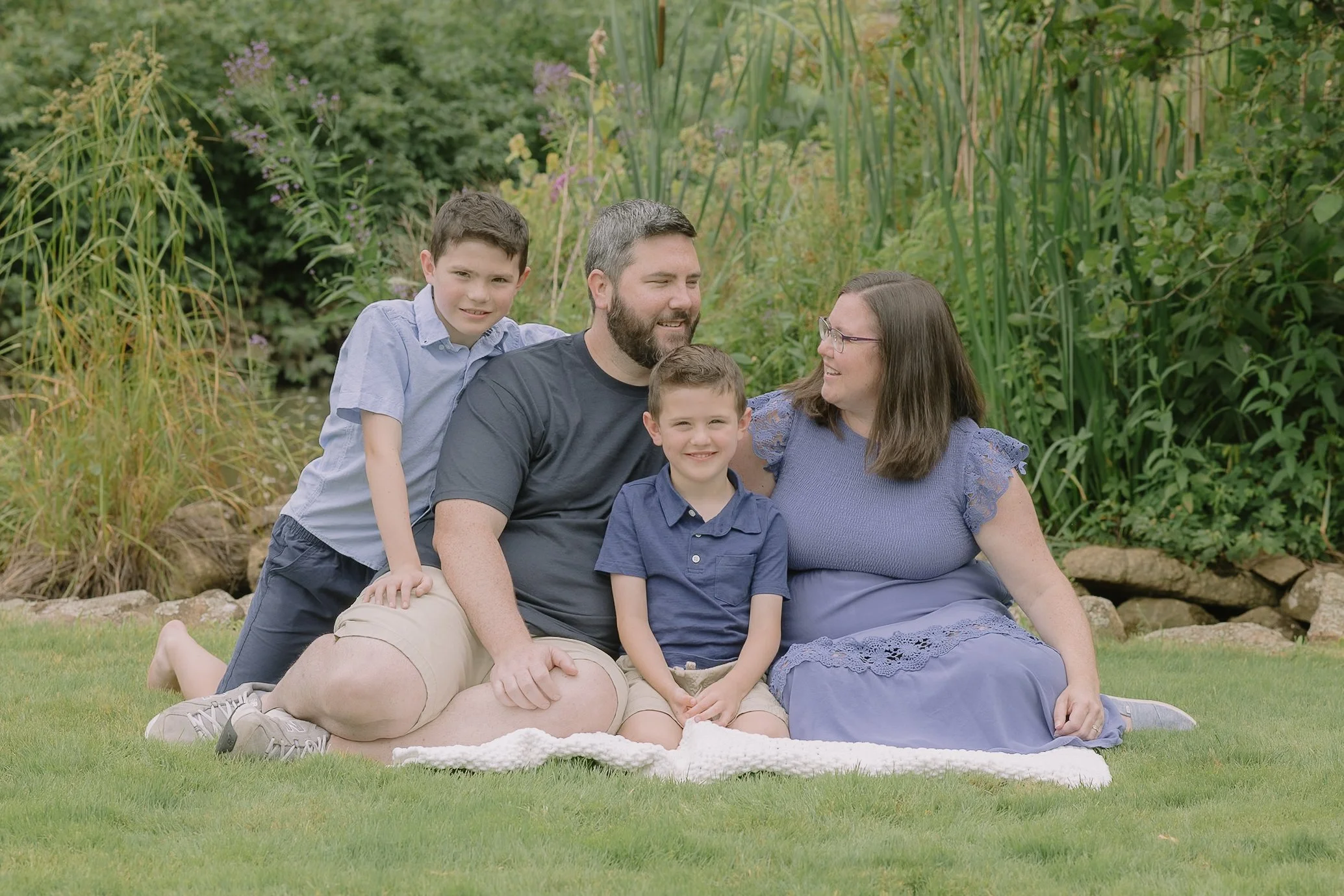 Family of four sitting in a grassy spot with blue outfits