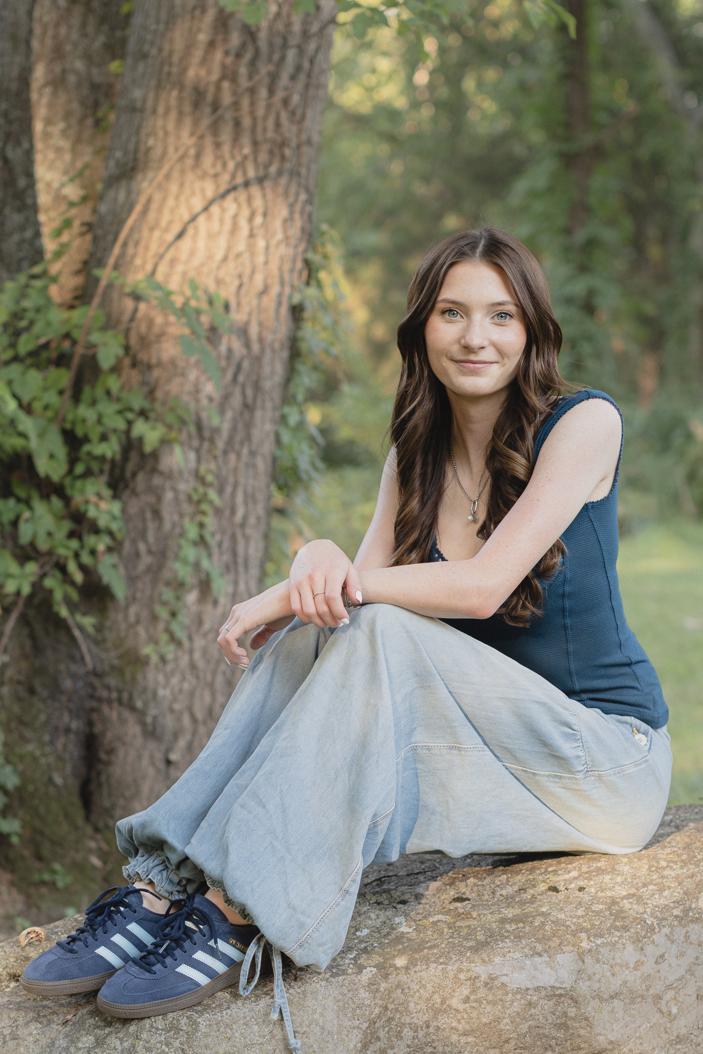 Young woman in blue top and jeans sitting on a rock