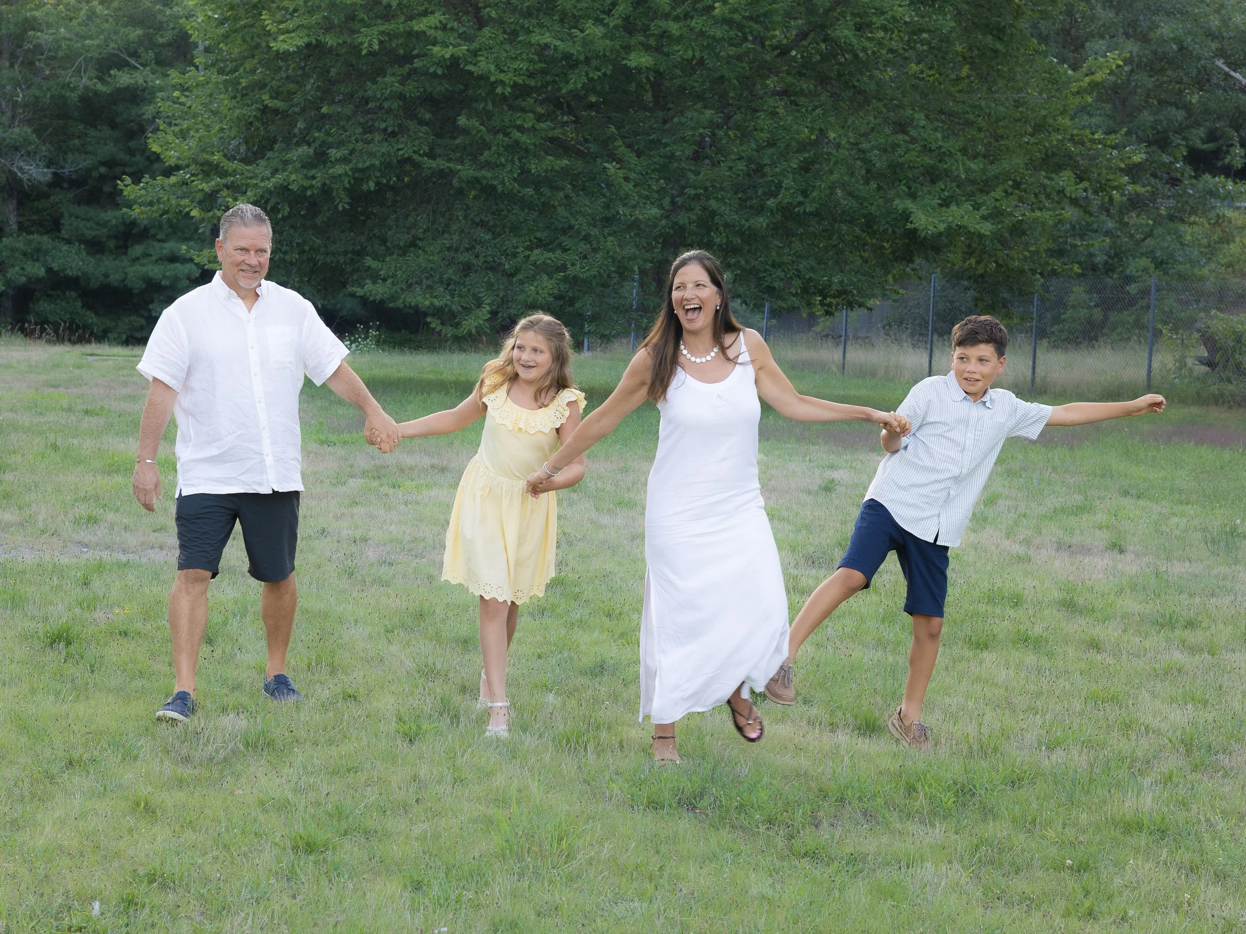Family holding hands in coordinated outfits in a field of green grass