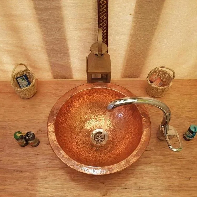 Rustic bathroom vanity with a polished copper basin sink at a desert trekking camp