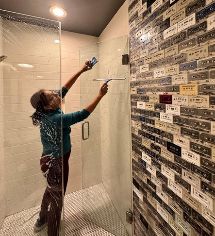 Employee of Karina's House and Office Cleaning actively cleaning a shower door
