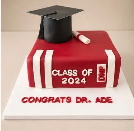 Graduation cap on decorated cake with red and white colors, displaying 'Class of 2024' and 'Congrats Dr. Ade'.
