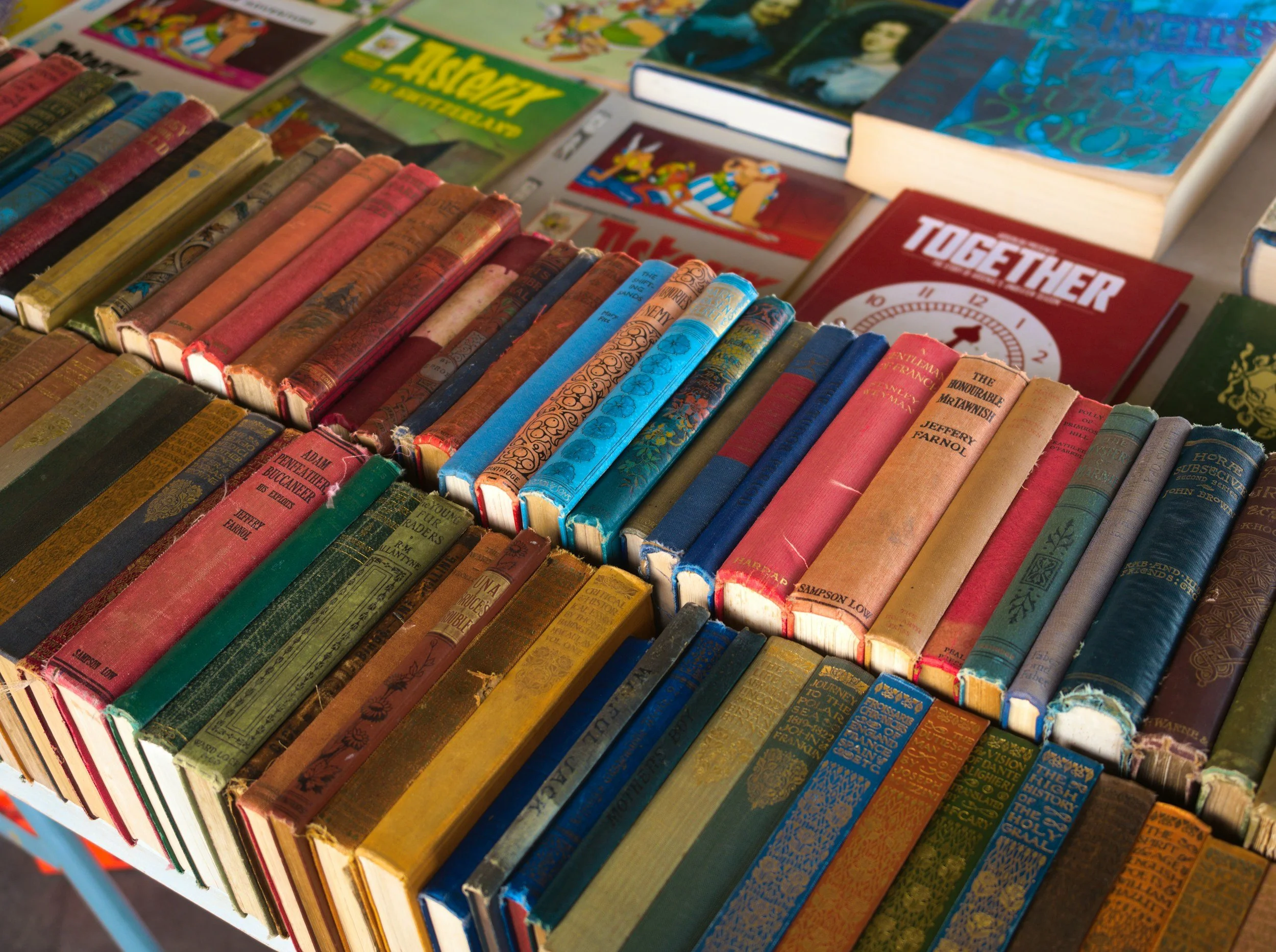 A collection of vintage hardcover and paperback books displayed on a table at a book sale or store. Titles include 'Togther' and various other titles with colorful, worn covers.