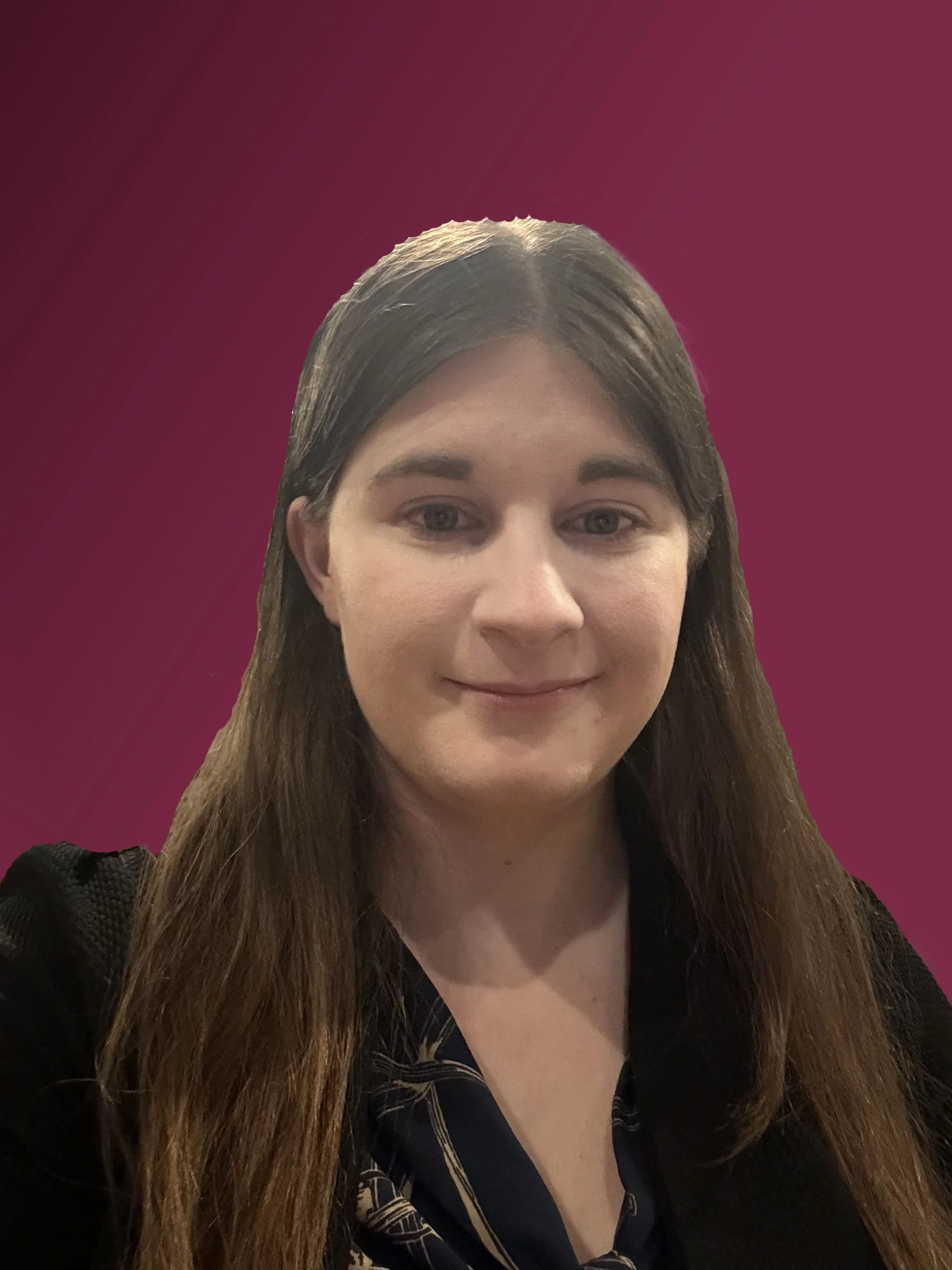A woman with long brown hair and fair skin, wearing a black top, smiling against a maroon gradient background.