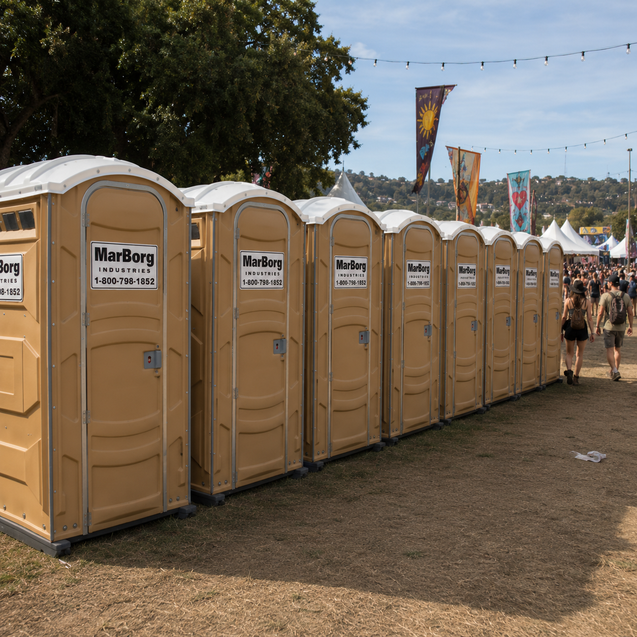 Multiple beige portable toilets with MarBorg Industries labels at outdoor festival with people walking, flags, and tents in the background.