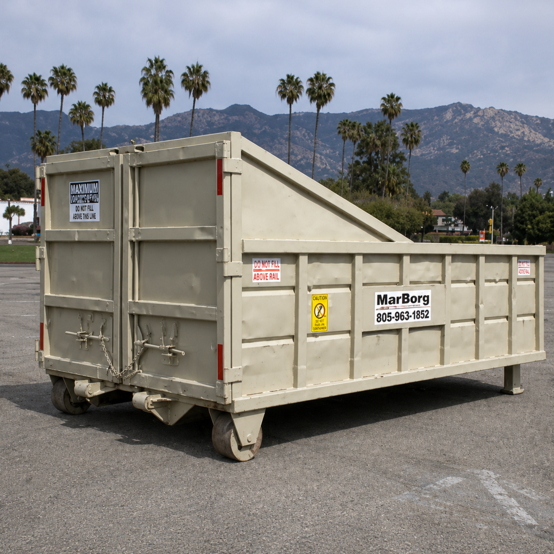 Roll-off container, mountains and trees in the background, and a cloudy sky.