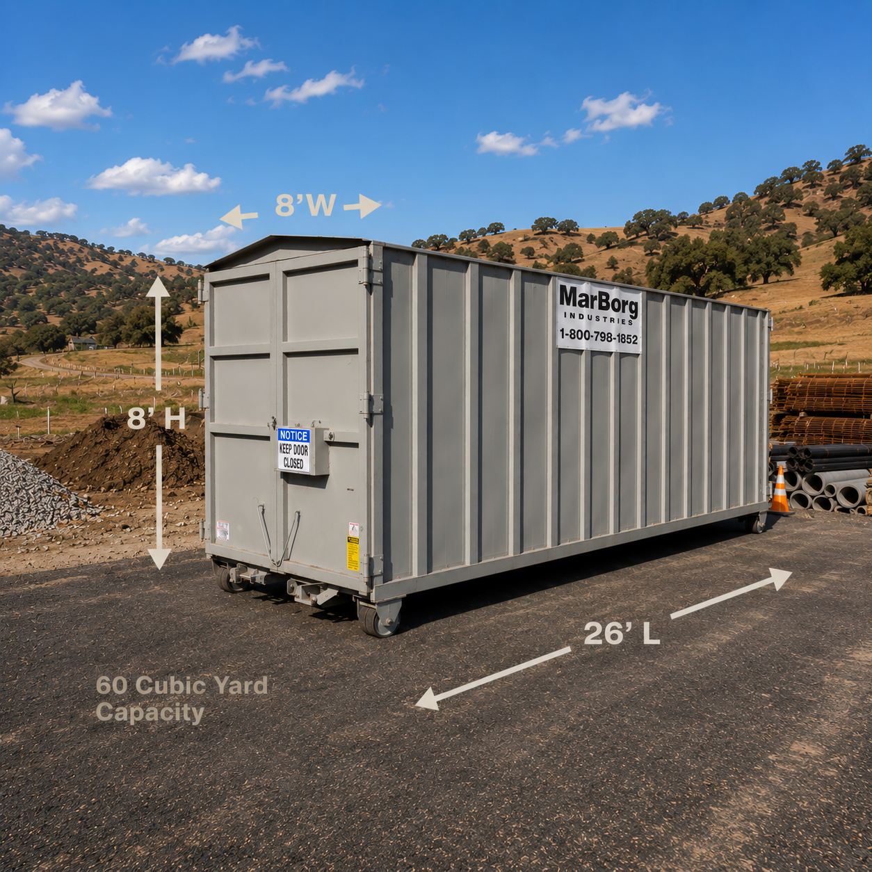 A 26' storage container resting on an asphalt pad with construction materials surrounding. Rolling hills in the background with blue skies overhead.