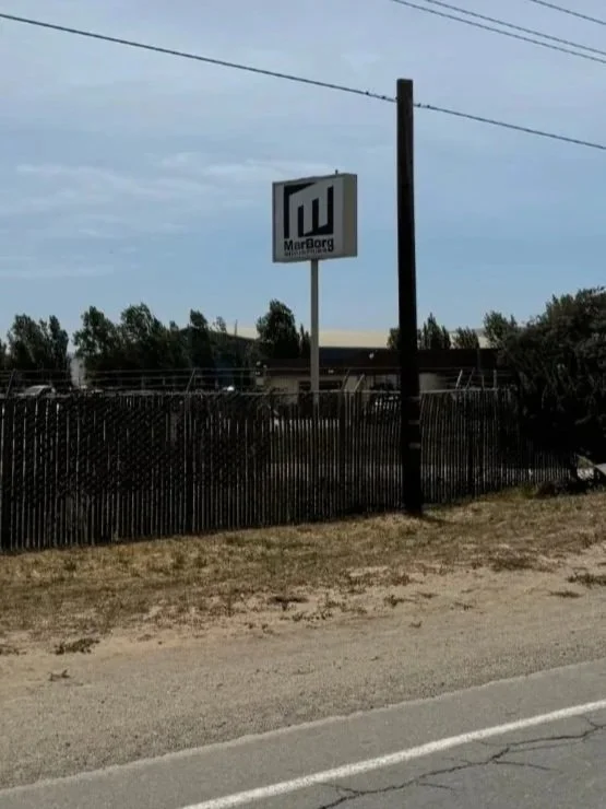Front entrance to the Santa Maria Recycling facility. A tall MarBorg sign stands just behind the fence with the office building sitting a few yards further behind.