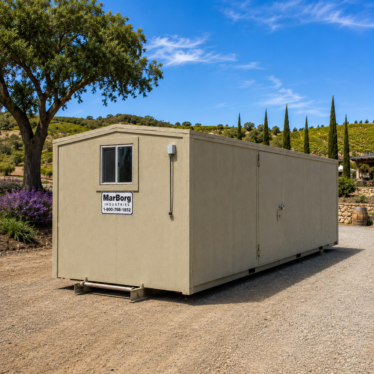 A large beige site office, in a beautiful central coast setting with a ranch home, stone wall and wine barrel in the background. 