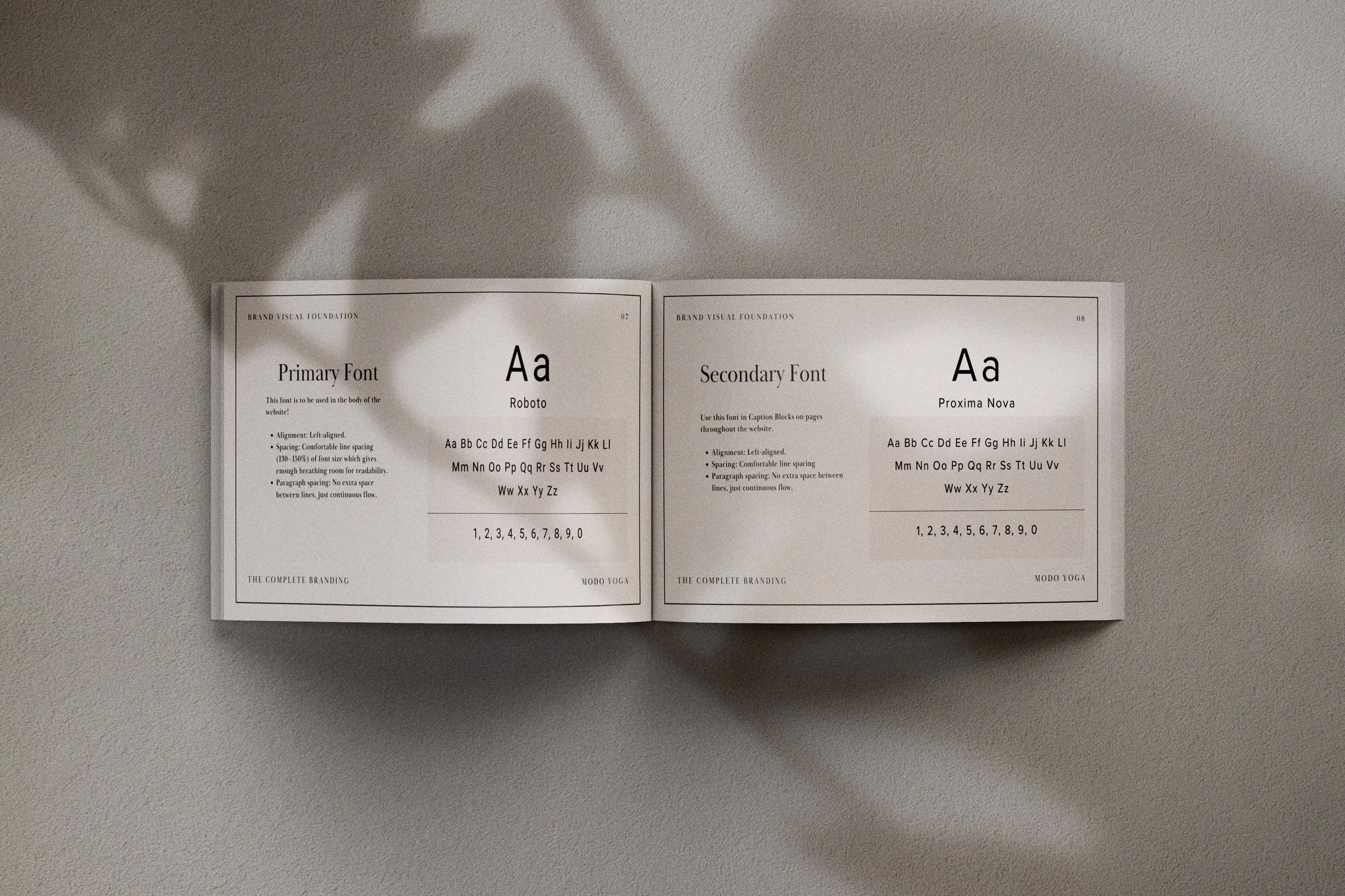 Open book showing font styles, with shadows on a textured gray surface.