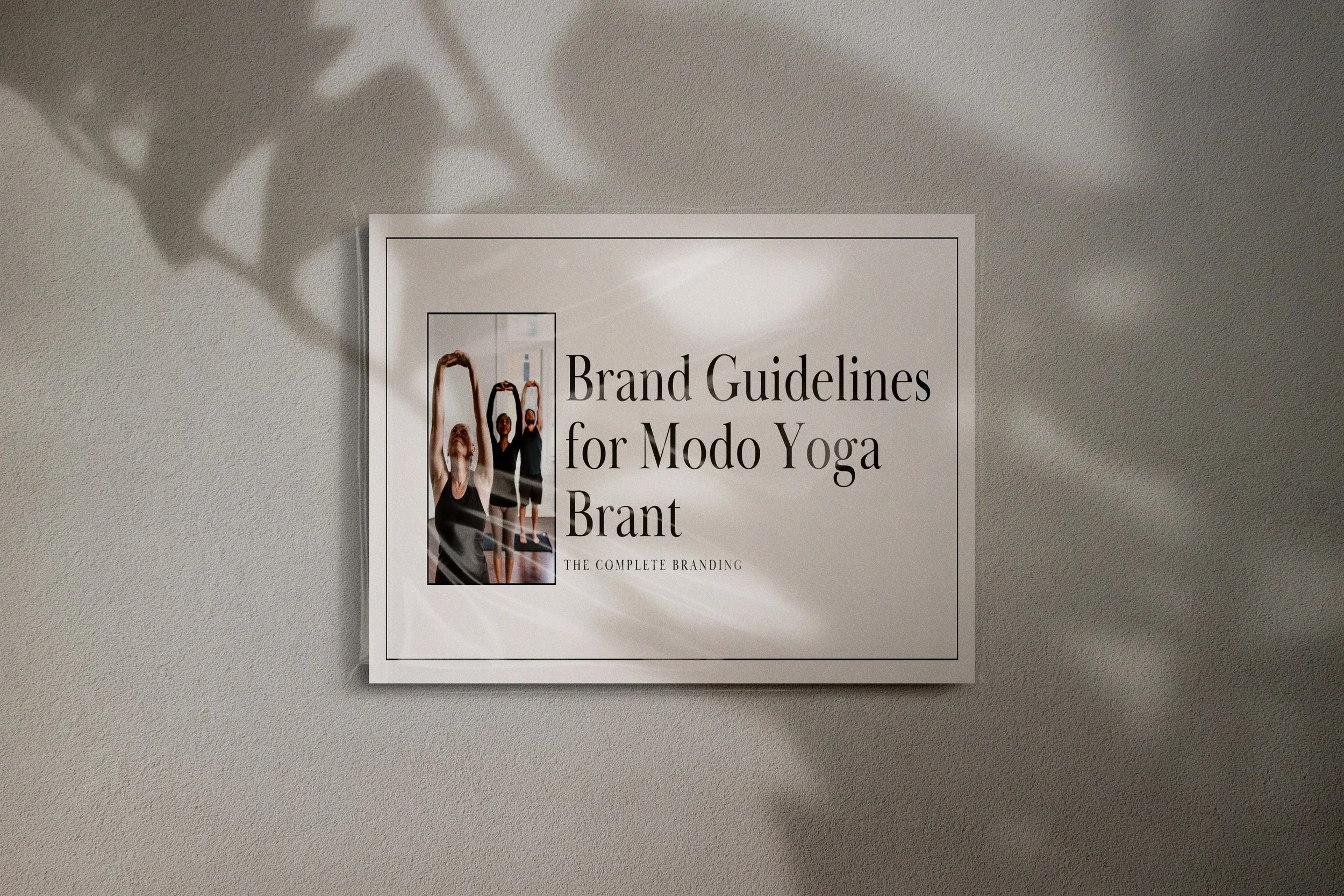 A poster on a wall titled 'Brand Guidelines for Modo Yoga Brant' featuring an image of three women doing yoga where one woman in the foreground is raising her arms above her head in a yoga pose.