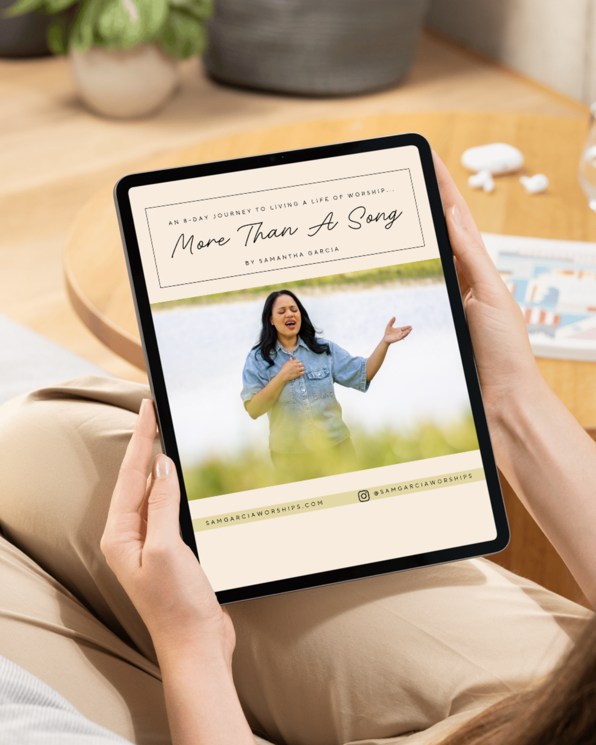 A person holding a tablet displaying a religious worship program titled 'More Than A Song' with an image of a woman singing passionately, outdoors on the screen.