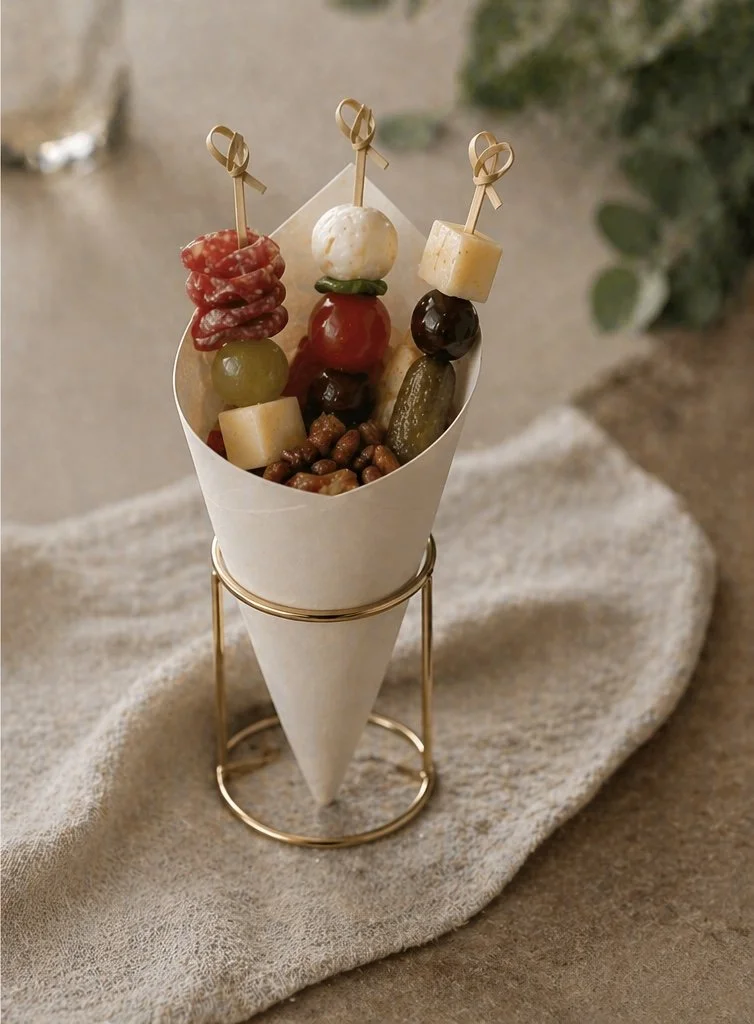 Skewers with various cheeses, fruits, and nuts in a cone-shaped holder.