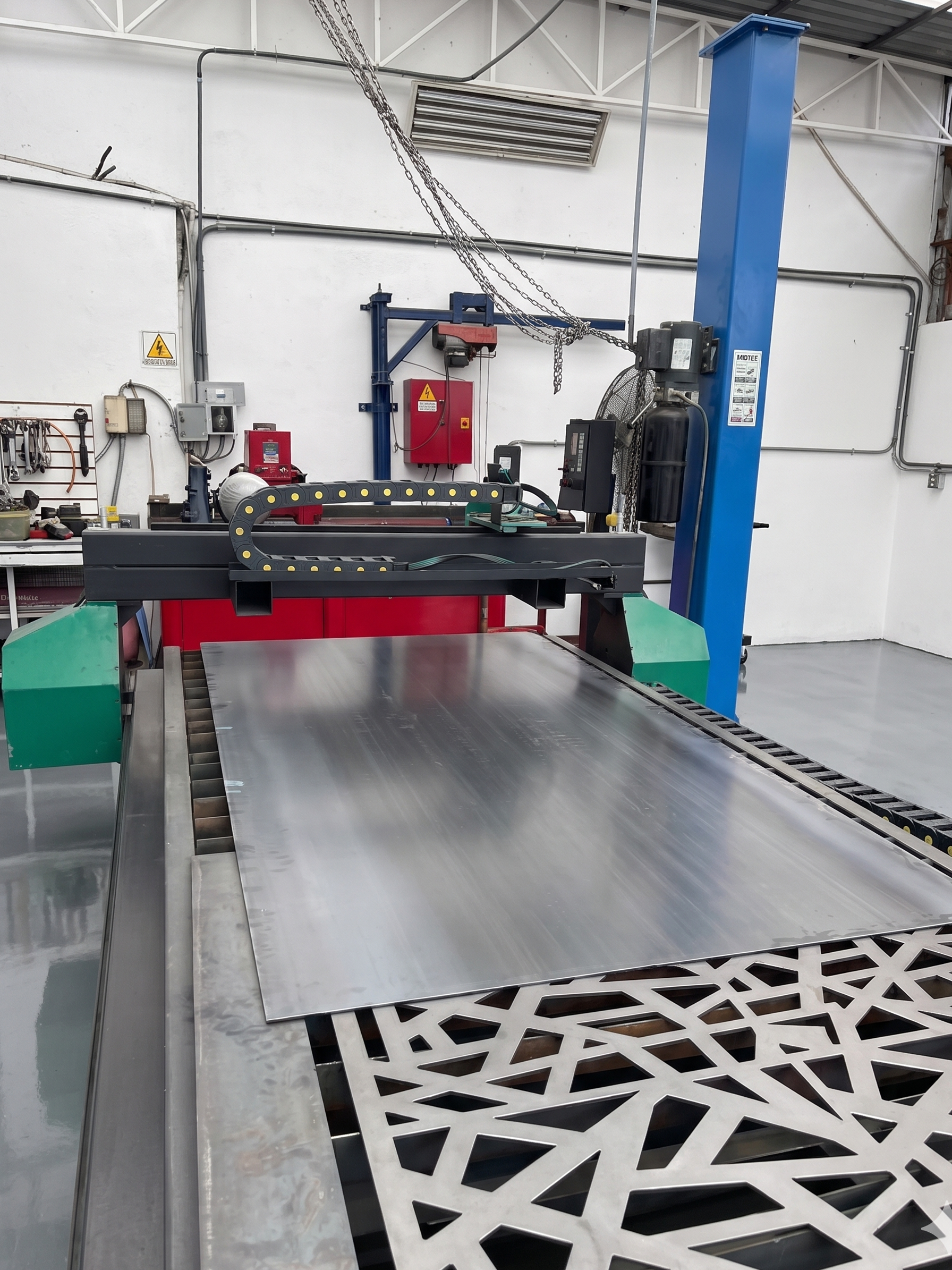 Vista de una línea de fabricación o taller industrial con maquinaria de metales y componentes de precisión, incluyendo una cinta transportadora y estructuras metálicas en un espacio limpio y organizado.