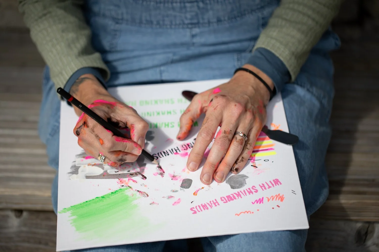 With Shaking Hands artist creating feminist art, hands with paint, rings and marker.