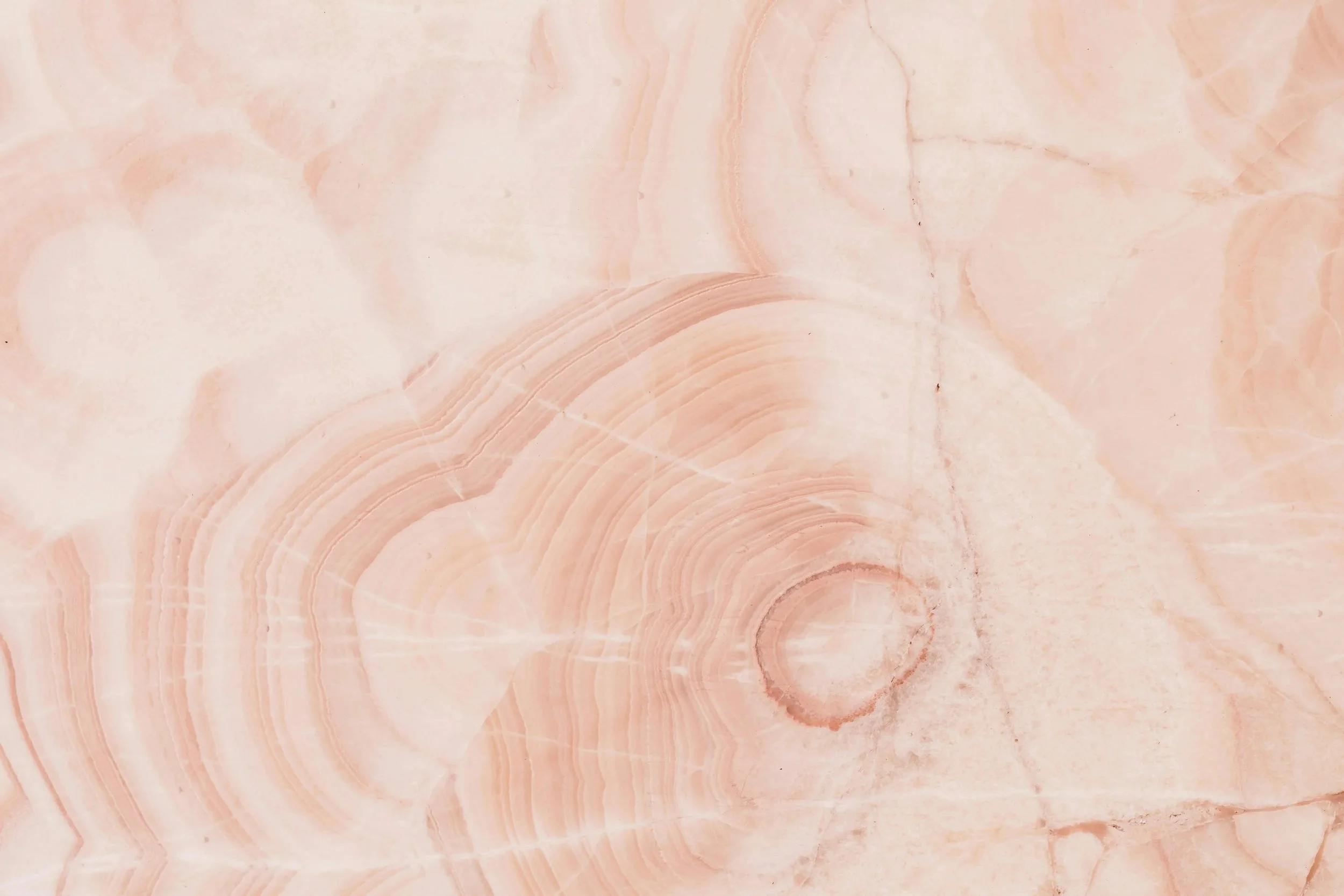 Close-up of pink onyx marble with natural veining and circular patterns.