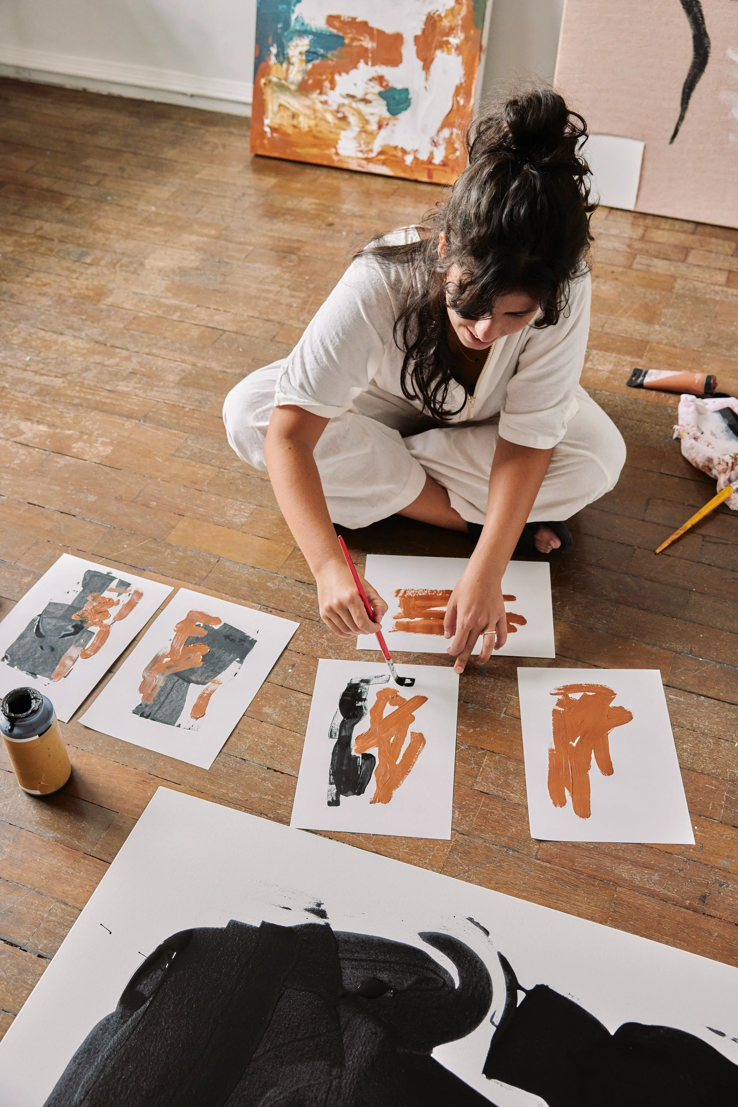 An adult drawing doing intuitive painting on the floor of a sunlit room.