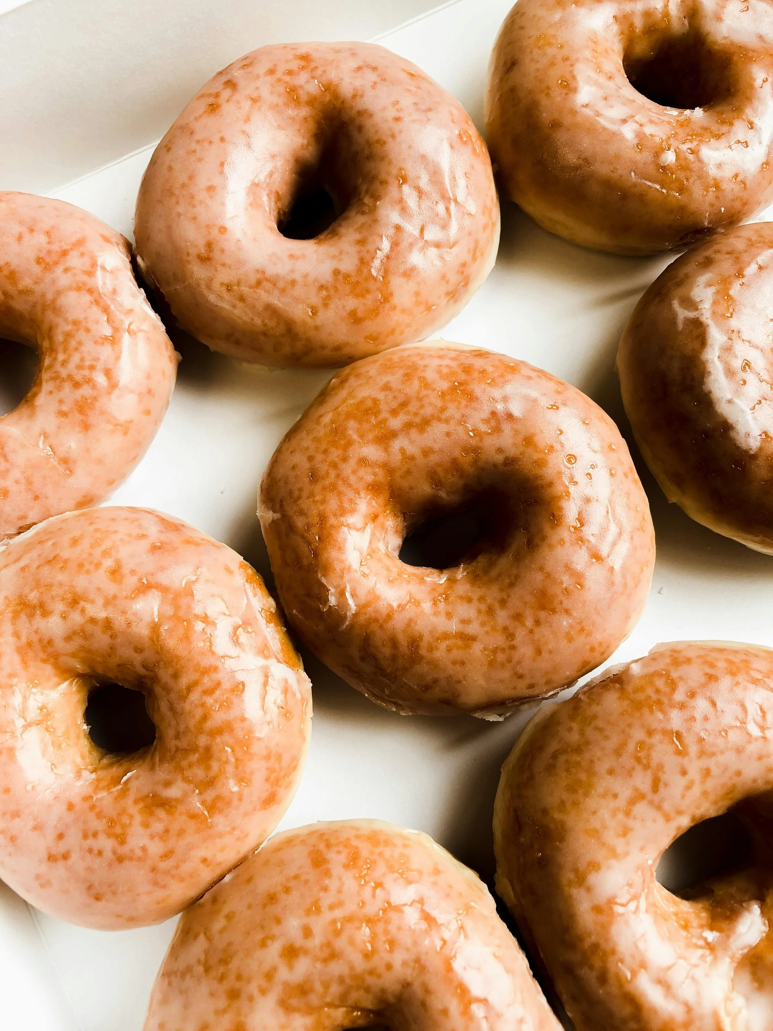 Close-up of glazed donuts on a white surface.