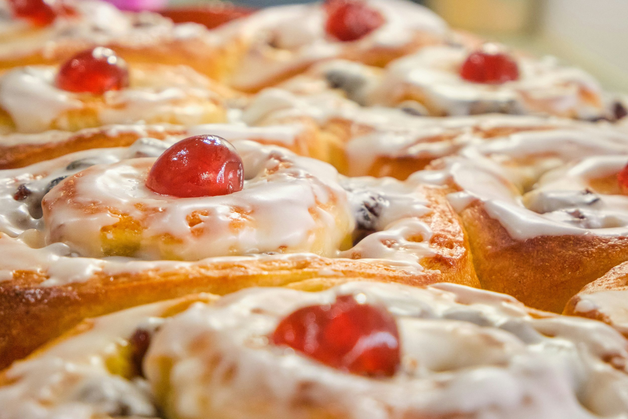 Close-up of a pizza topped with cherries, white glaze, and various fruits and nuts.