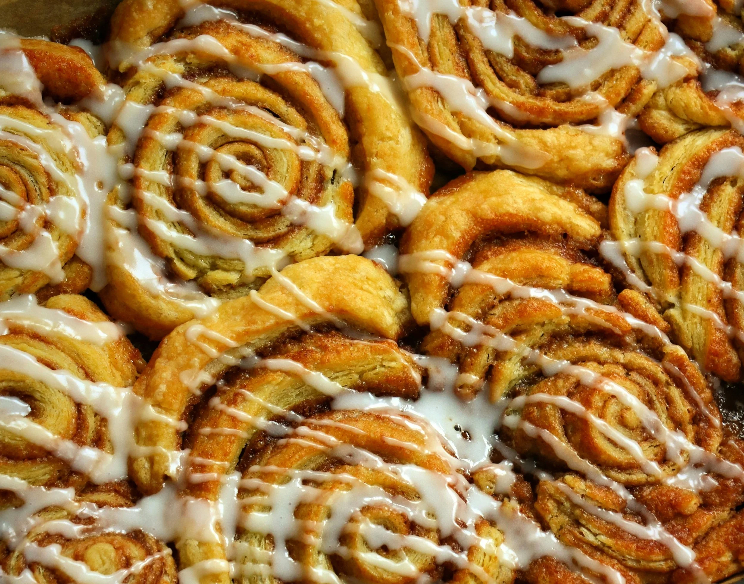 Close-up view of cinnamon rolls drizzled with icing.
