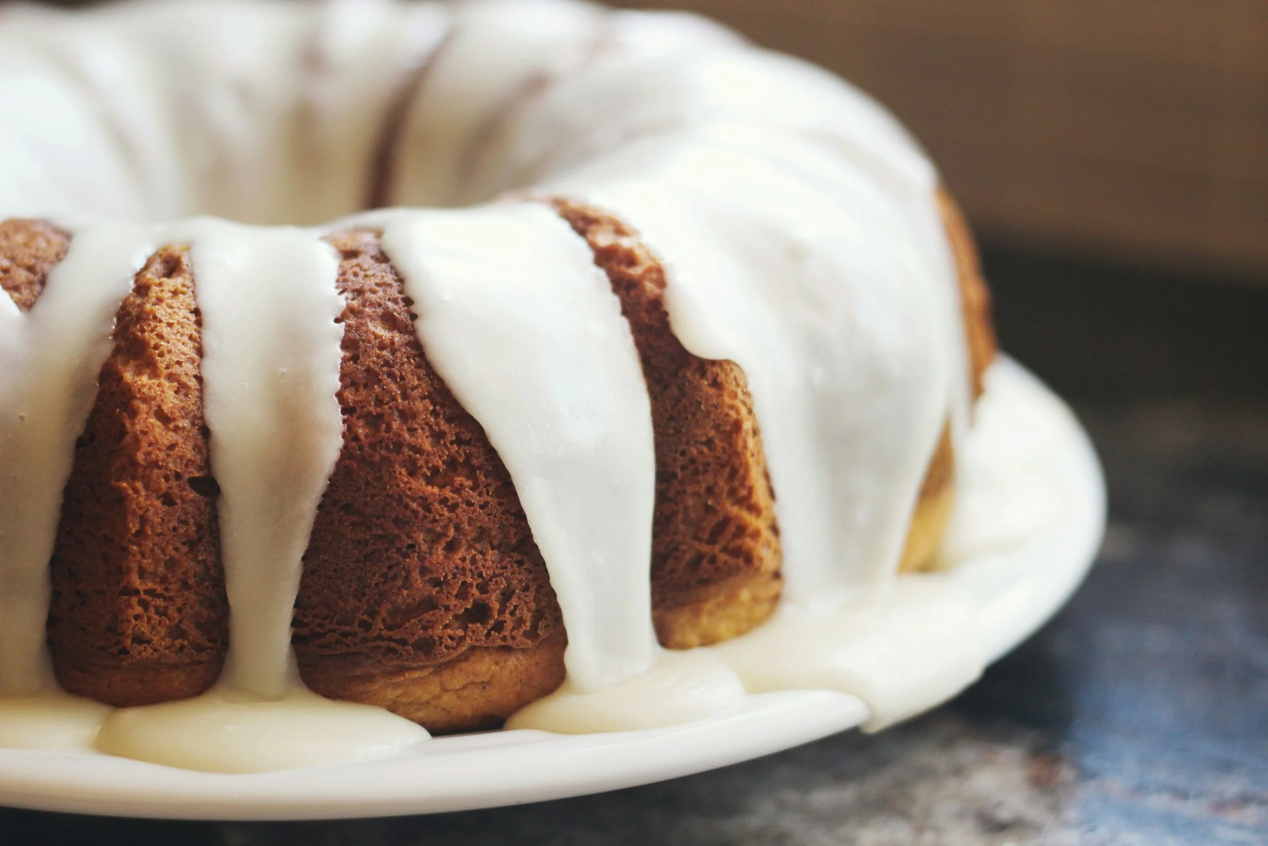 Close-up of a bundt cake topped with white icing, showing moist, dense texture of the cake slices.