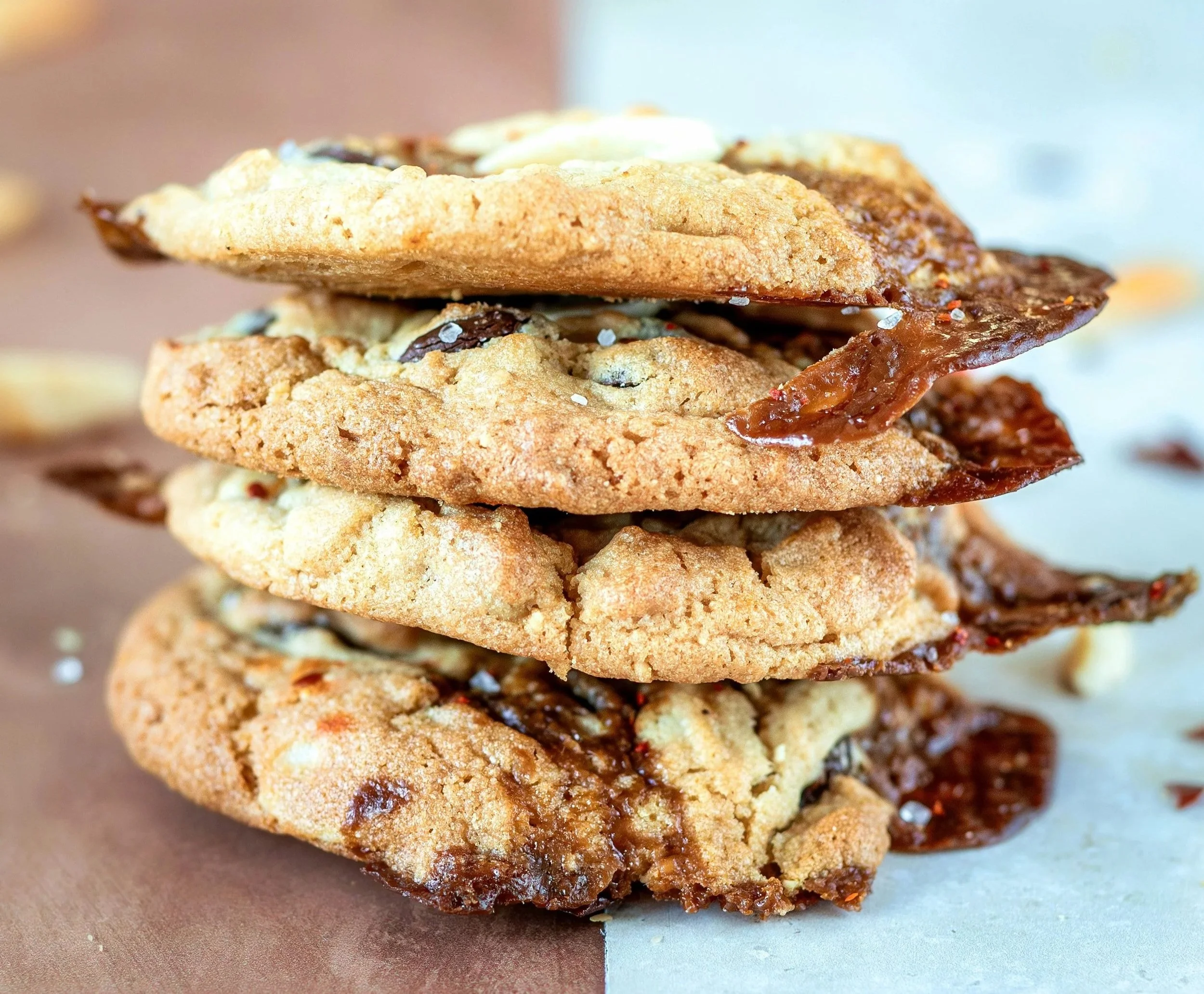 Stacked cookies with chocolate chips and a drizzle of caramel, shown in close-up.