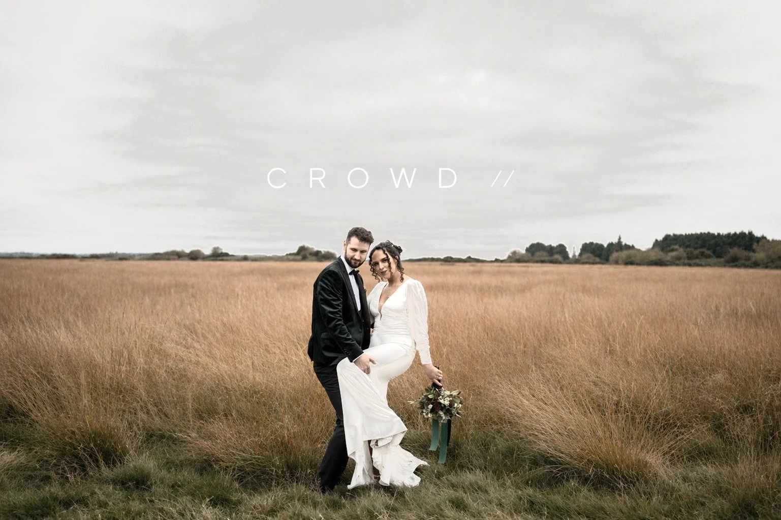 Wedding couple standing in a field of tall grass under an overcast sky, with the word 'CROWD' written above them.